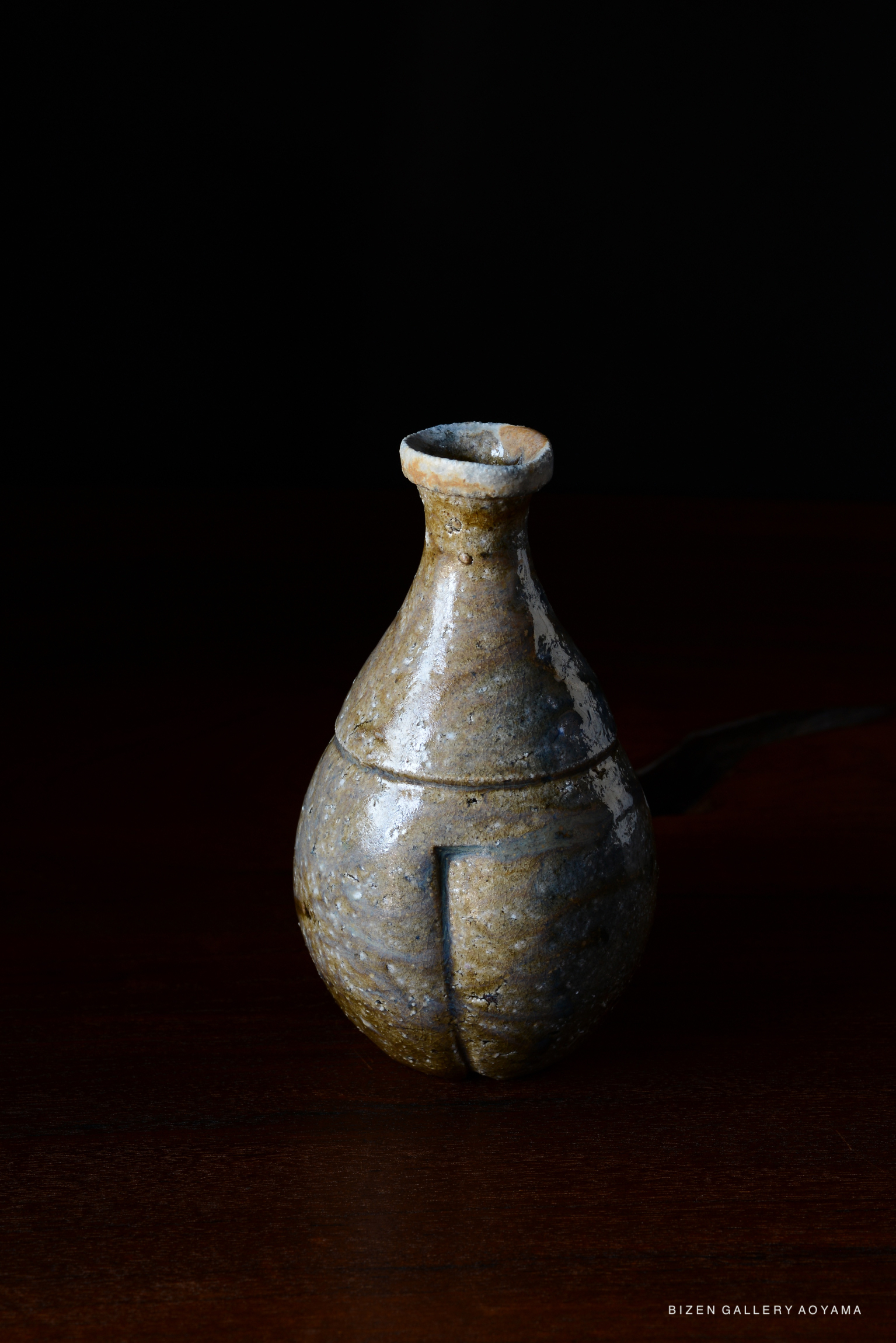 A traditional Bizen pottery vase with a bulbous body and a narrow neck, featuring natural glazes and a unique texture, set against a dark background.