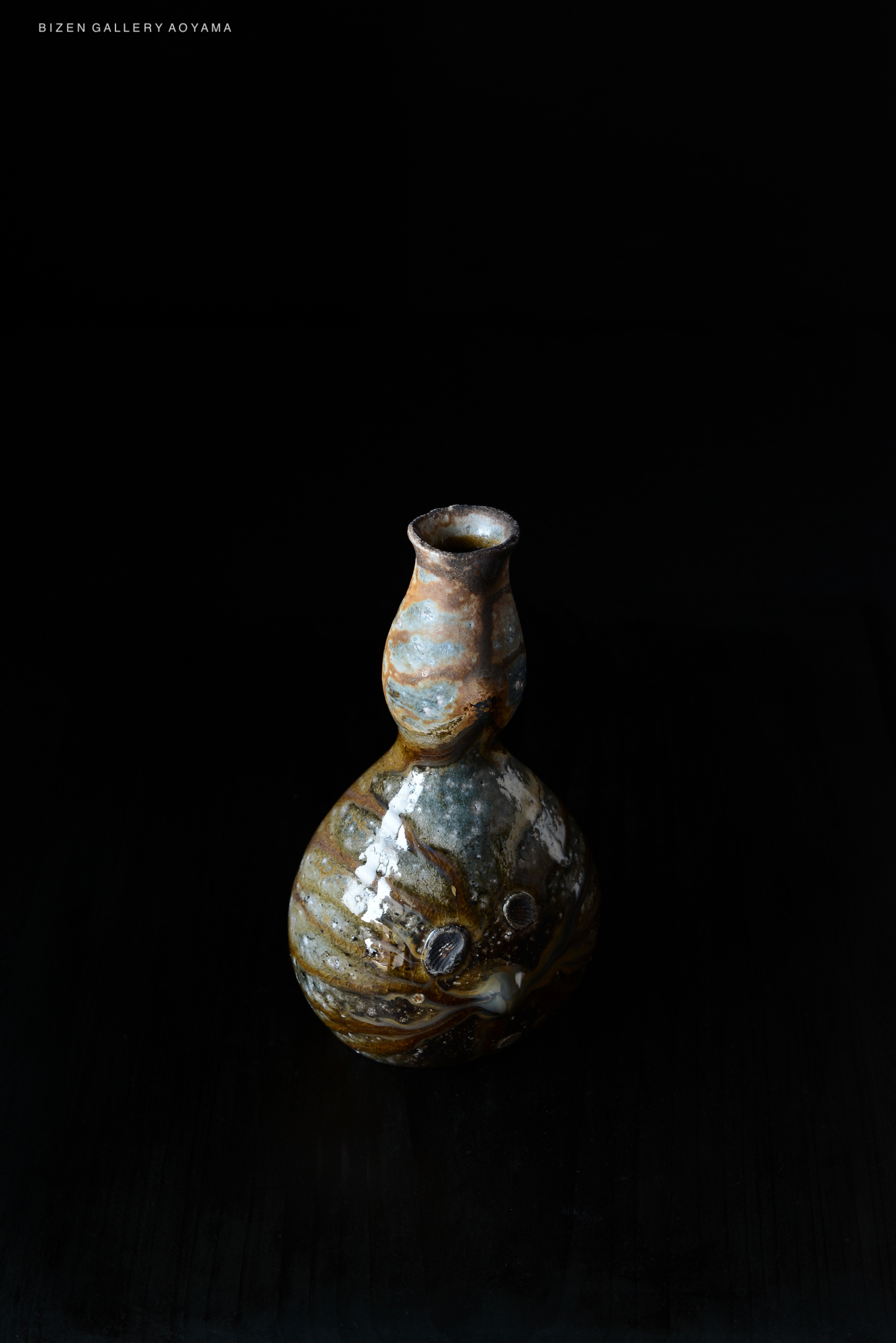 A traditional Bizen pottery vase with a unique shape and textured surface, displayed against a dark background.