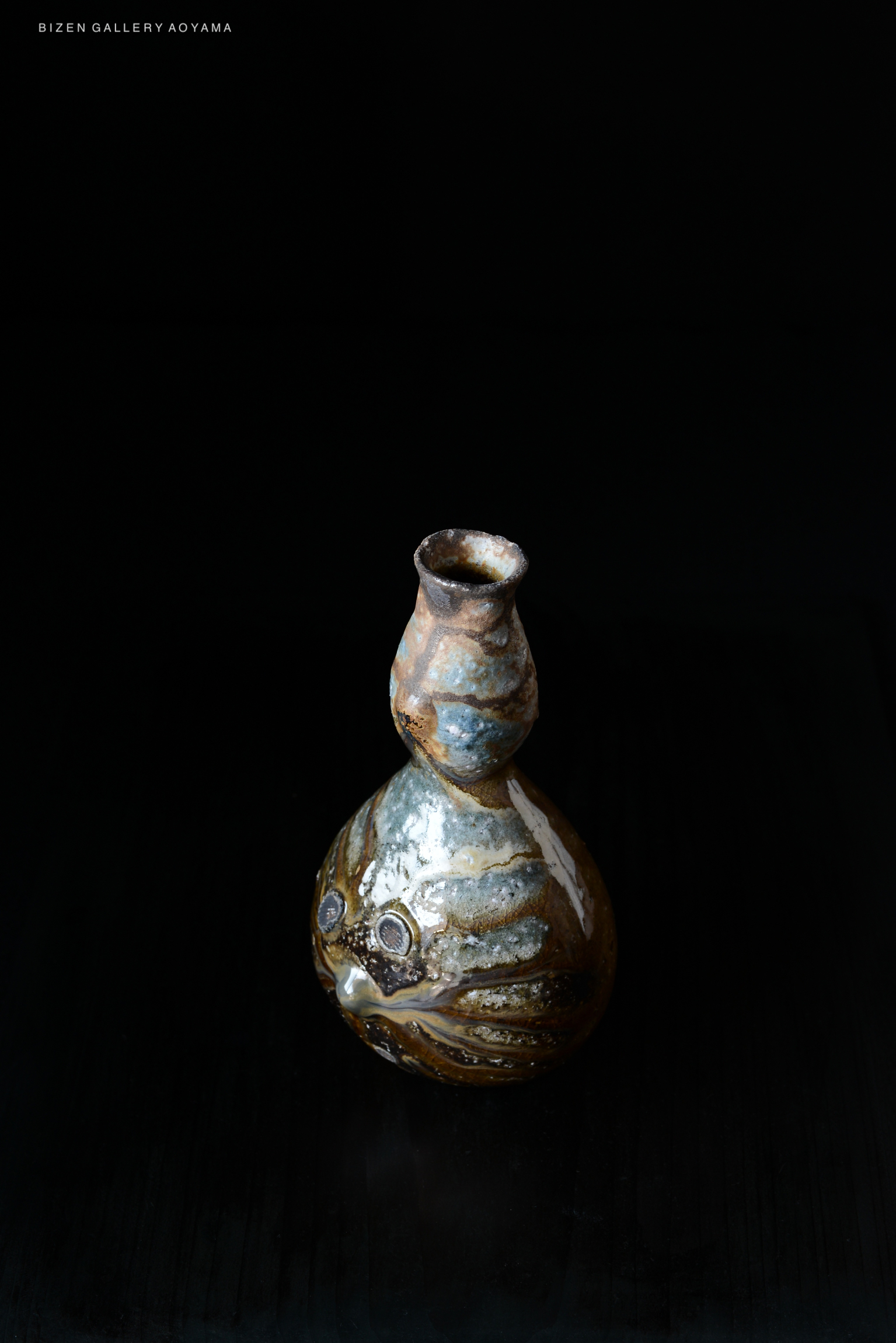 A handcrafted ceramic vase with a unique shape and texture, featuring a glossy finish and earthy colors, set against a black background.