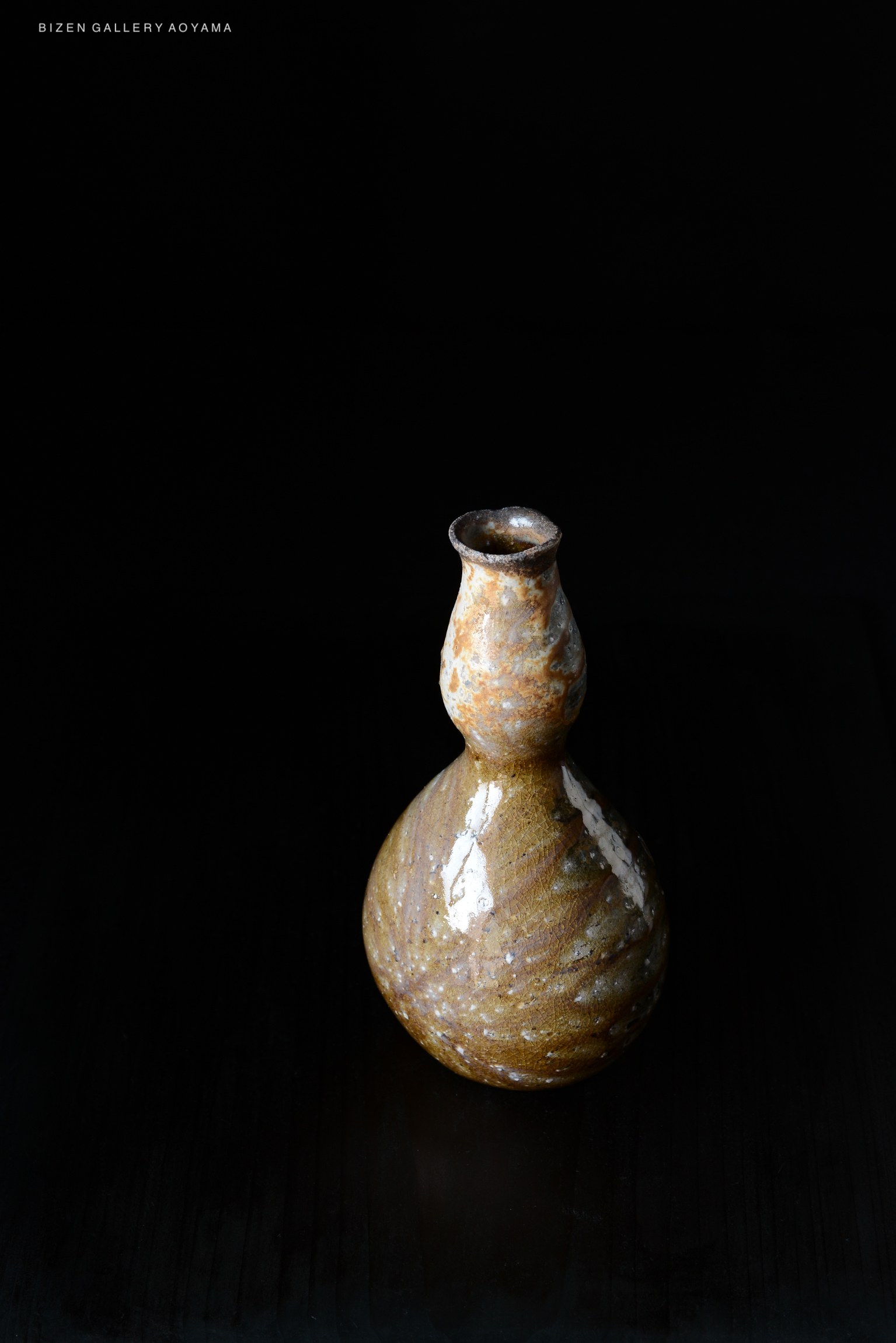 A small, elegant Bizen pottery vase with a textured, spiraled design and a narrow neck, set against a black background.