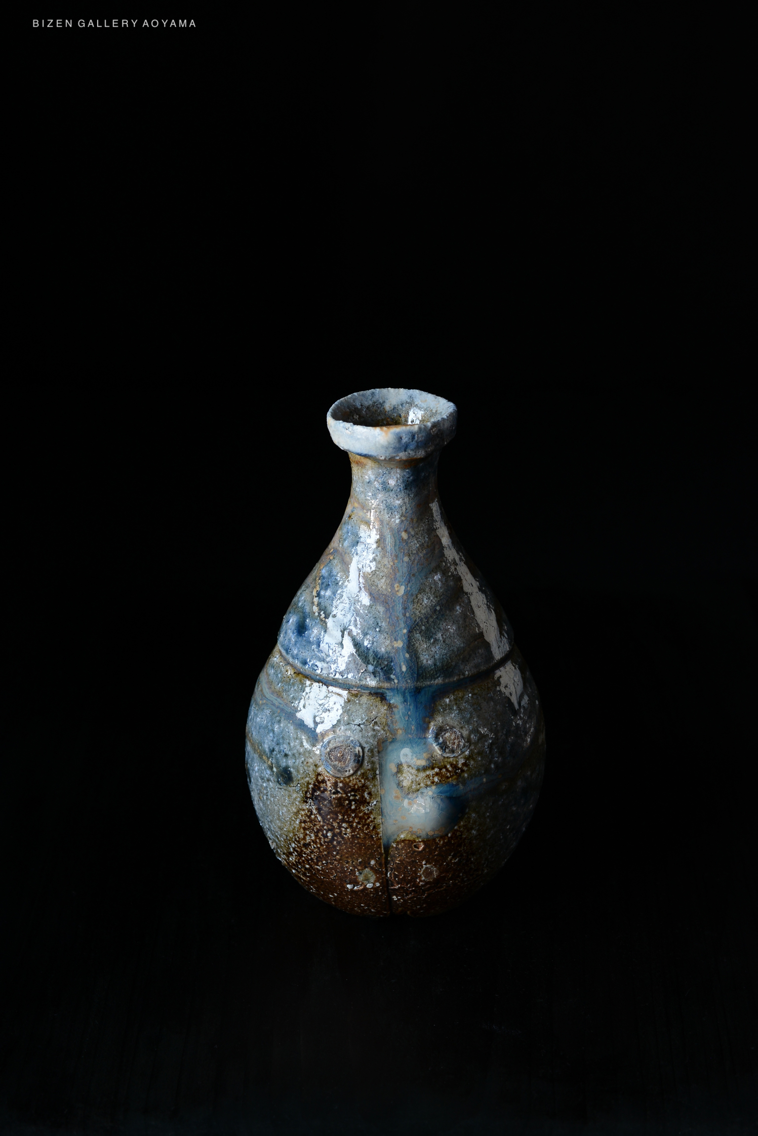 A traditional Bizen pottery vase with a unique, textured surface featuring shades of blue and brown, displayed against a black background.