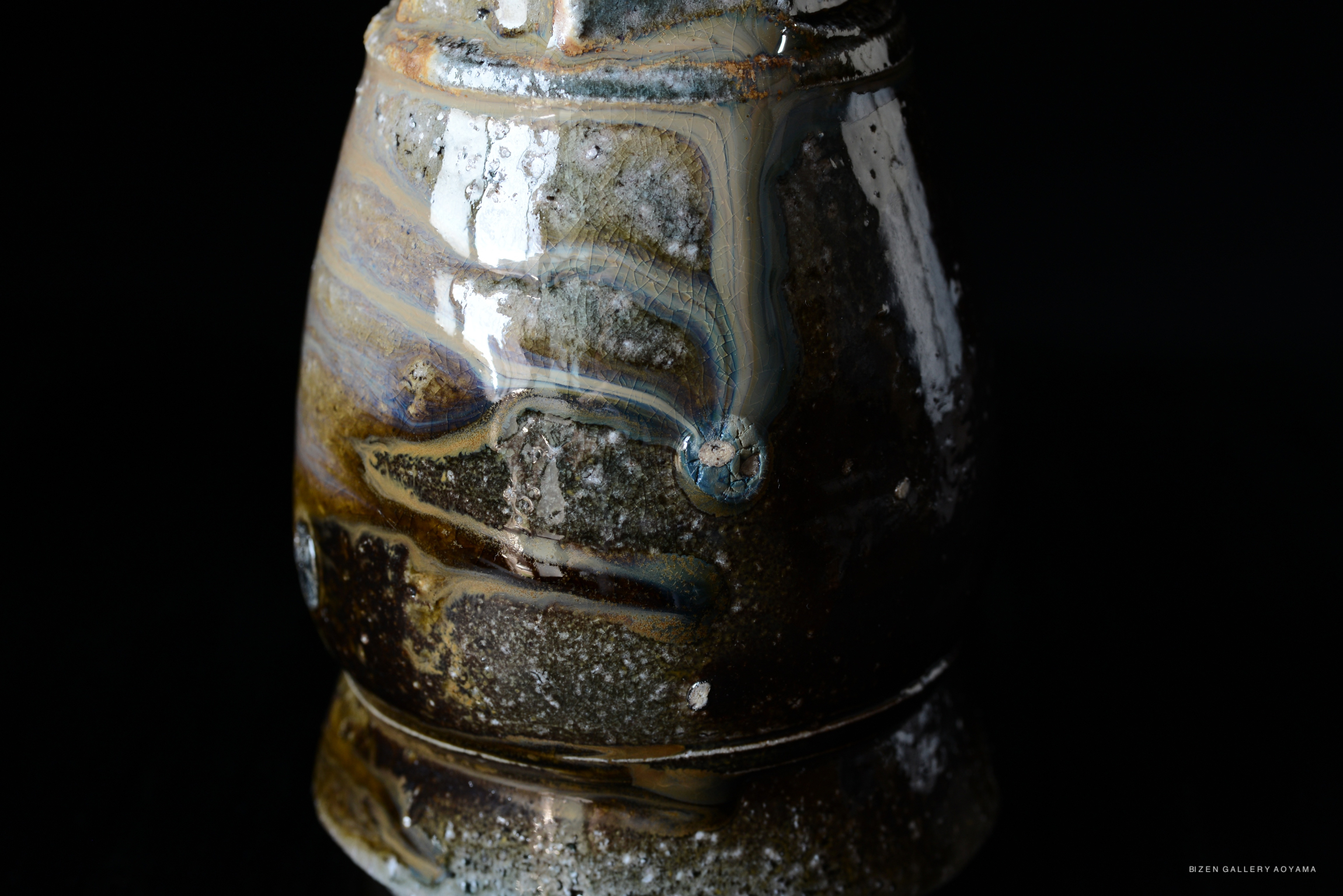 Close-up of a Kuro Tokkuri (black sake bottle) showcasing intricate glaze patterns and textures against a dark background.