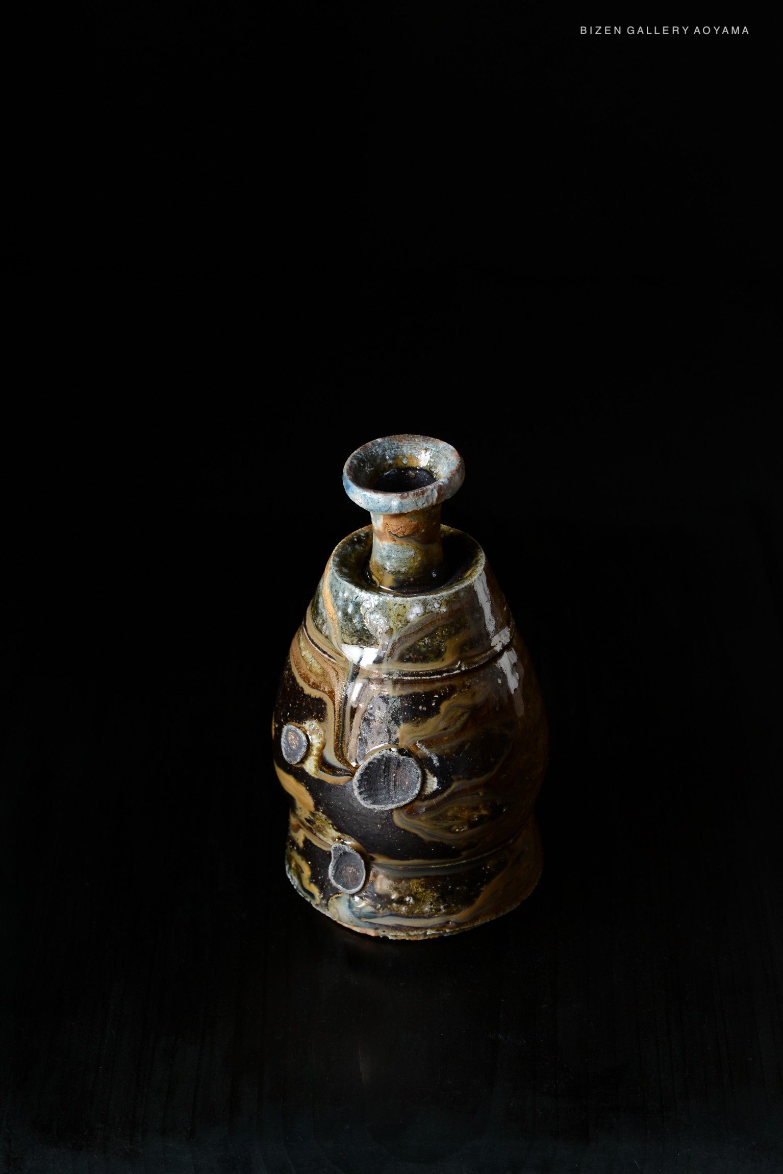 A traditional Japanese Kuro Tokkuri, or sake bottle, showcasing earthy tones and textured patterns, set against a black background.