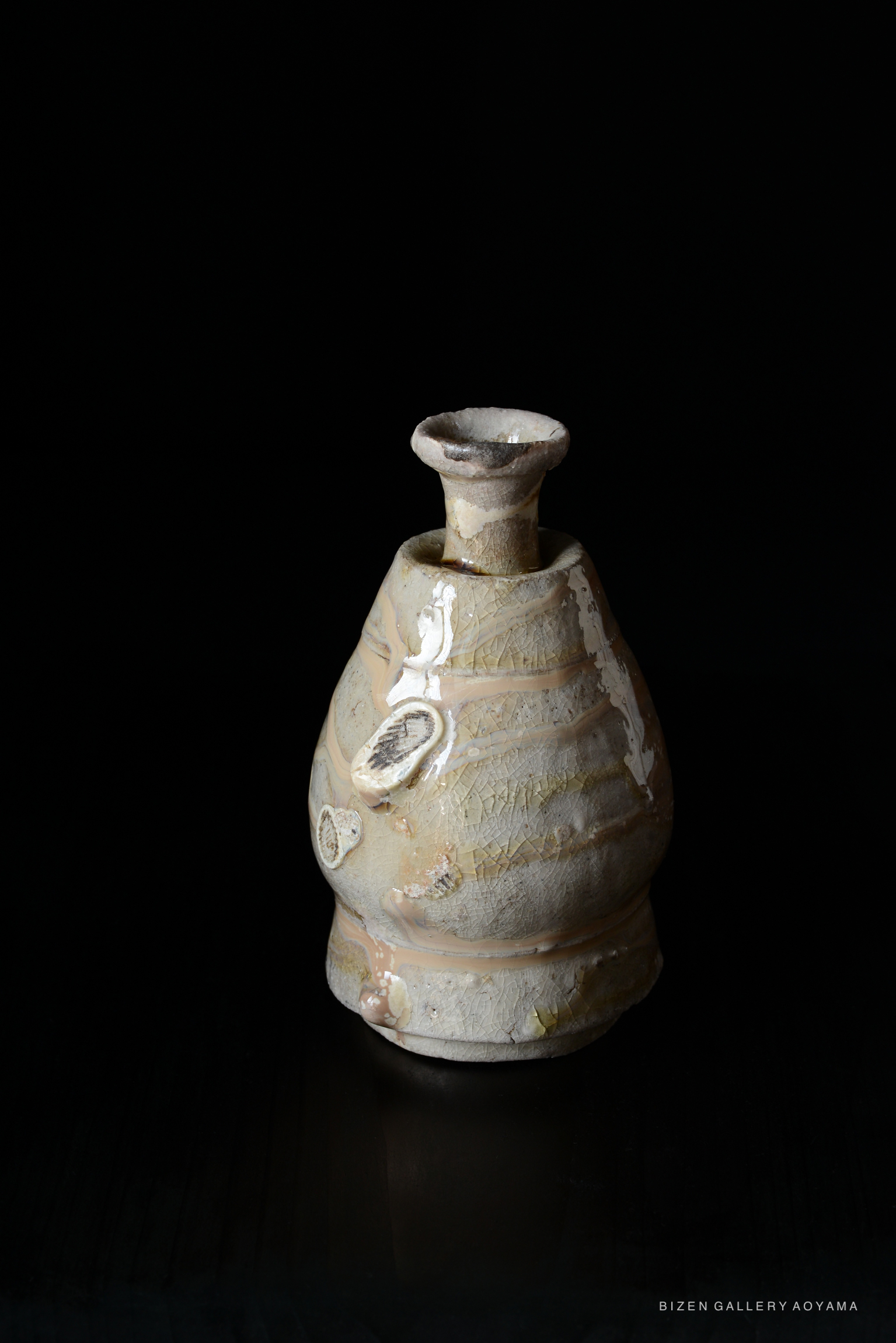 A traditional Shiro Tokkuri sake vessel made of Bizen pottery, showcasing a unique shape and textured surface with natural glaze variations, set against a black background.