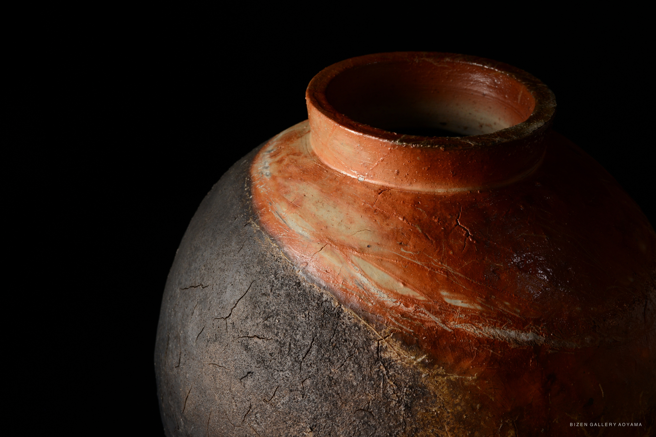 A close-up of a beautifully crafted pottery vessel, showcasing a blend of earthy tones with a textured surface and a smooth opening.