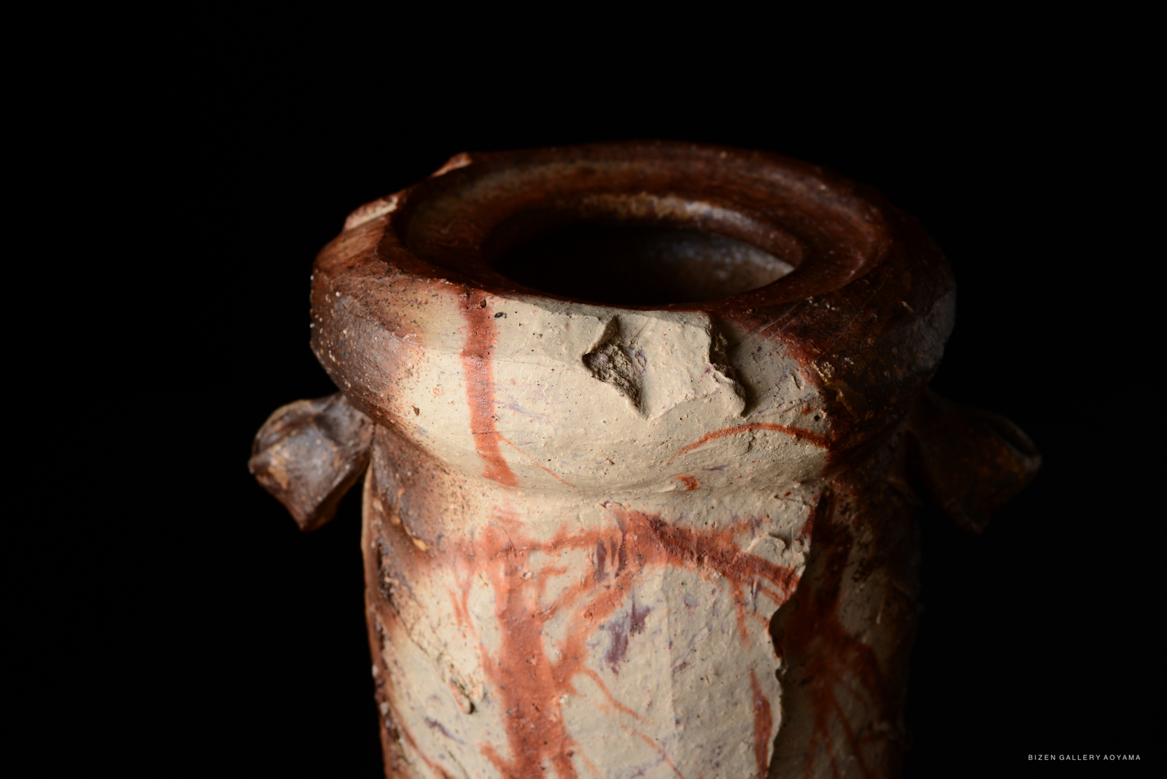 Close-up of the top of a ceramic vase showcasing a textured rim and earthy colors.