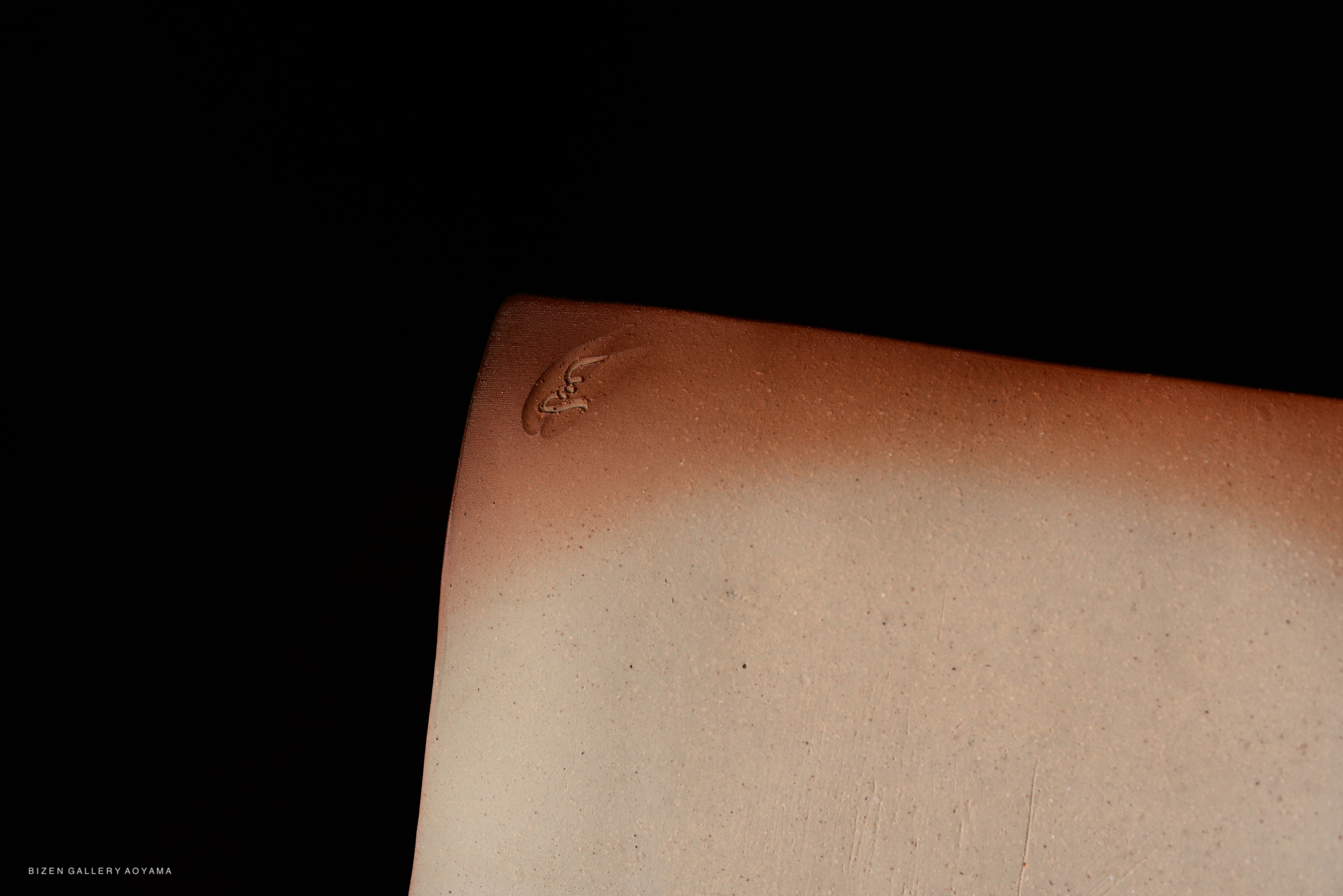 Close-up of a ceramic piece showcasing a subtle texture and a unique signature.