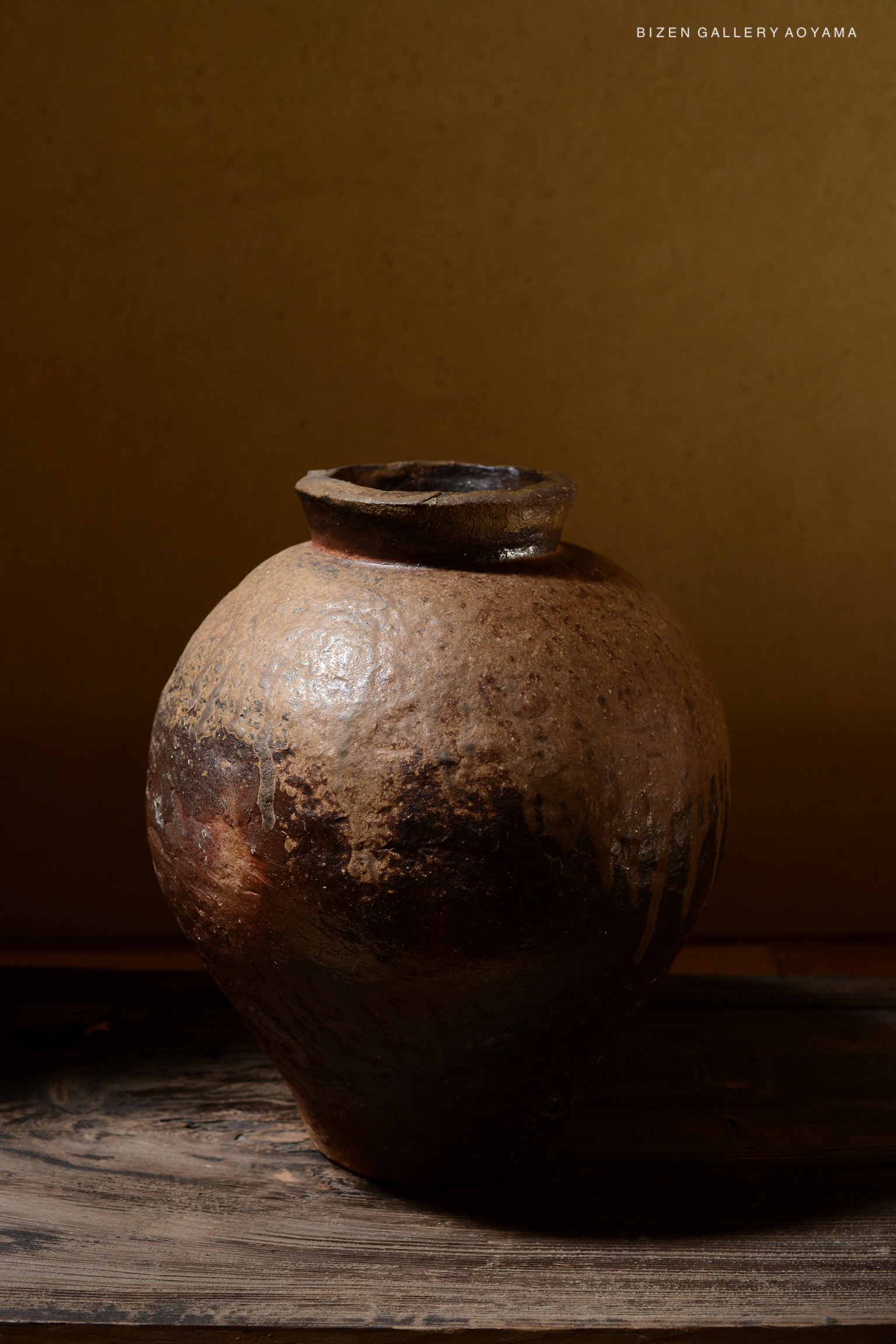 A rustic pottery jar with a rounded body and a narrow neck, set against a plain background.