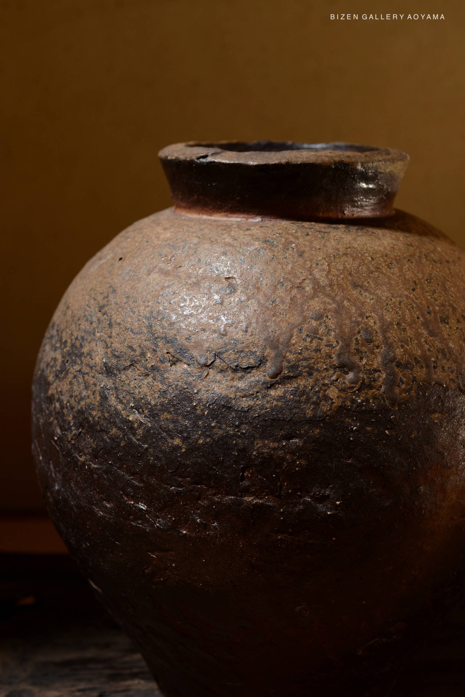 Close-up of a traditional Bizen pottery vase with a textured surface and dark, earthy colors.