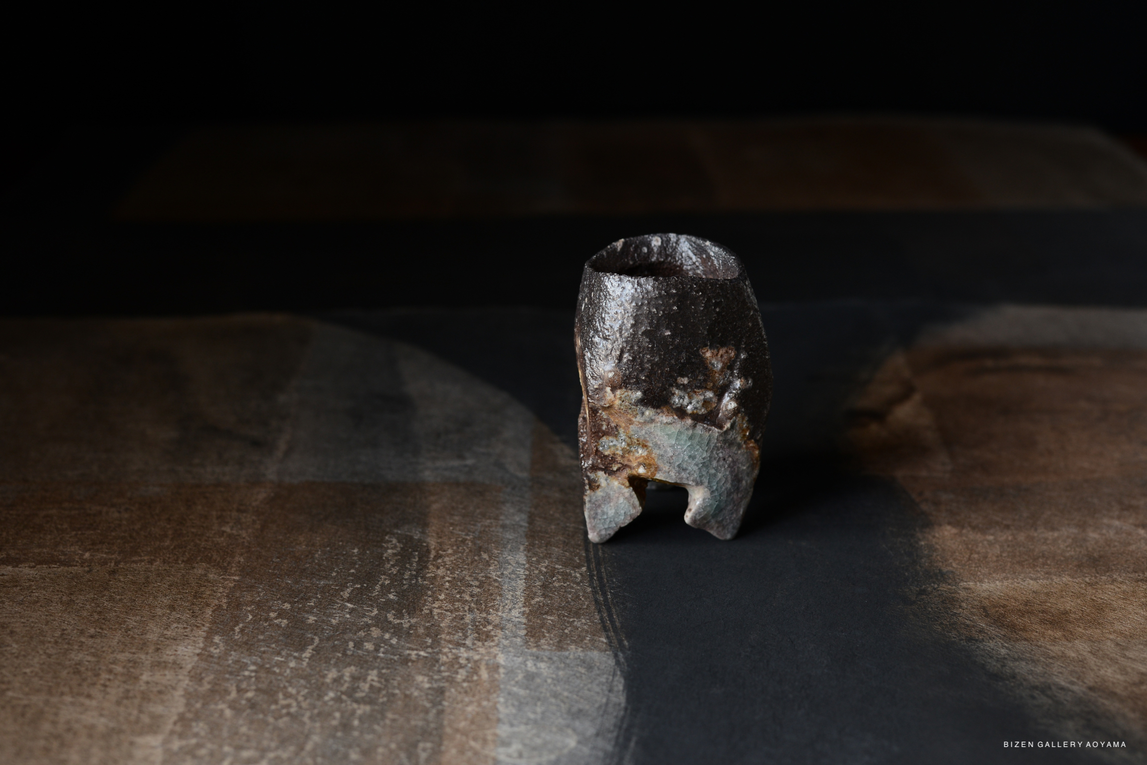 A striking ceramic piece with a textured surface, set against a dark textured background.