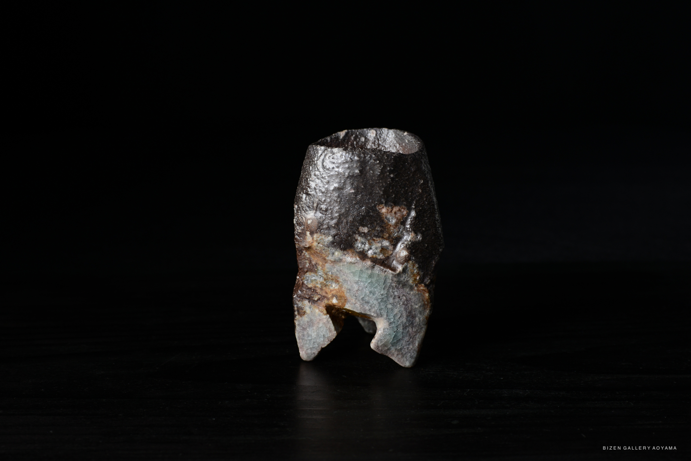 A unique Bizen ware ceramic piece, showcasing an irregular shape and textured surface against a dark background.