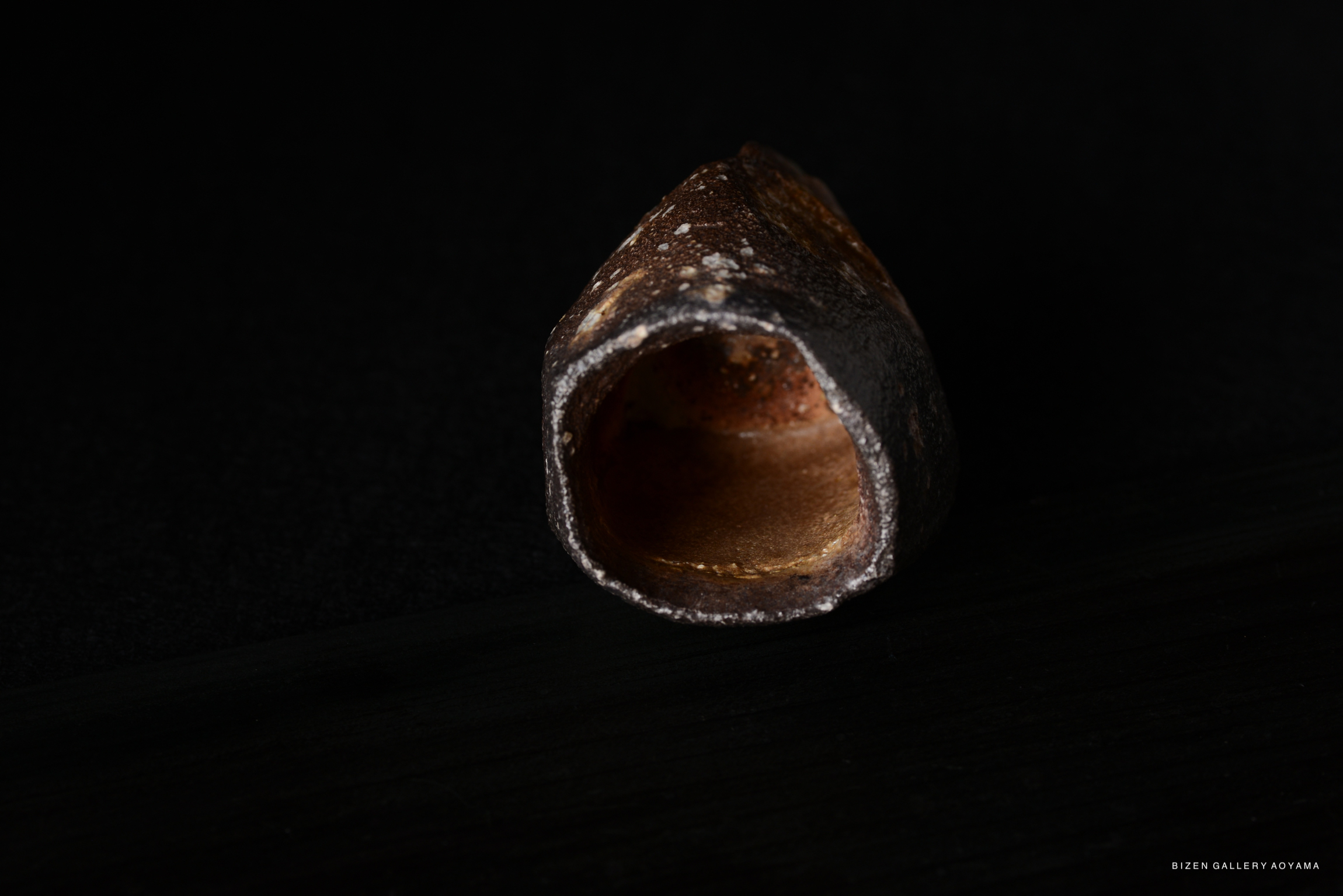 Close-up of a textured ceramic piece displayed against a dark background.