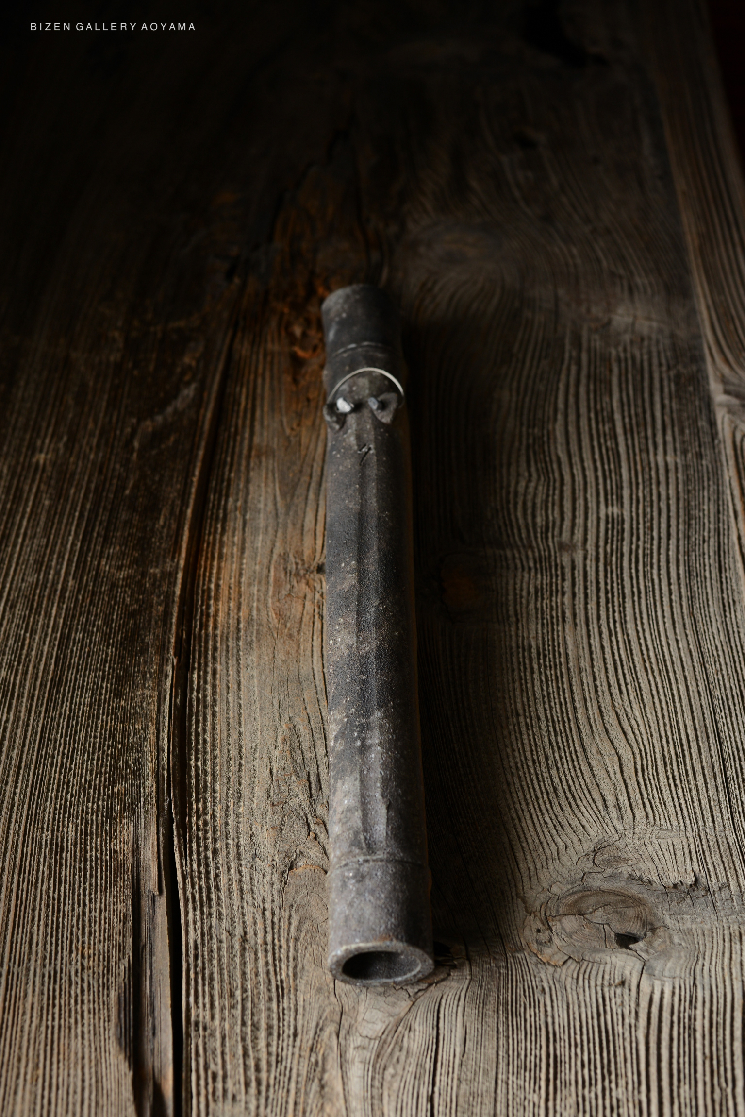 A traditional Bizen pottery piece resting on rustic wooden surface, showcasing its unique shape and texture.