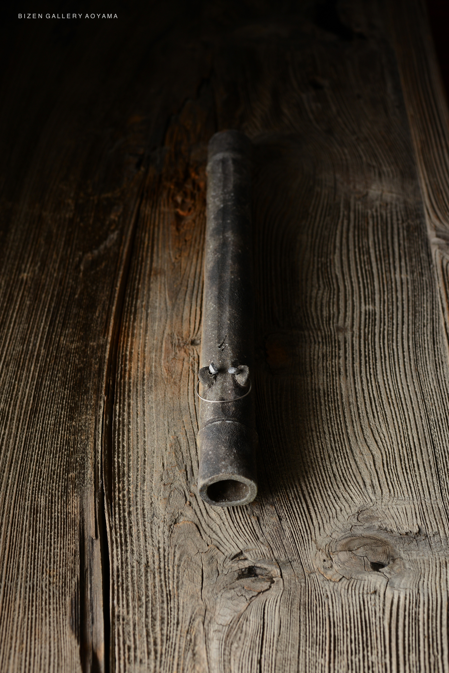 A close-up of a traditional Bizen pottery piece resting on a wooden surface.