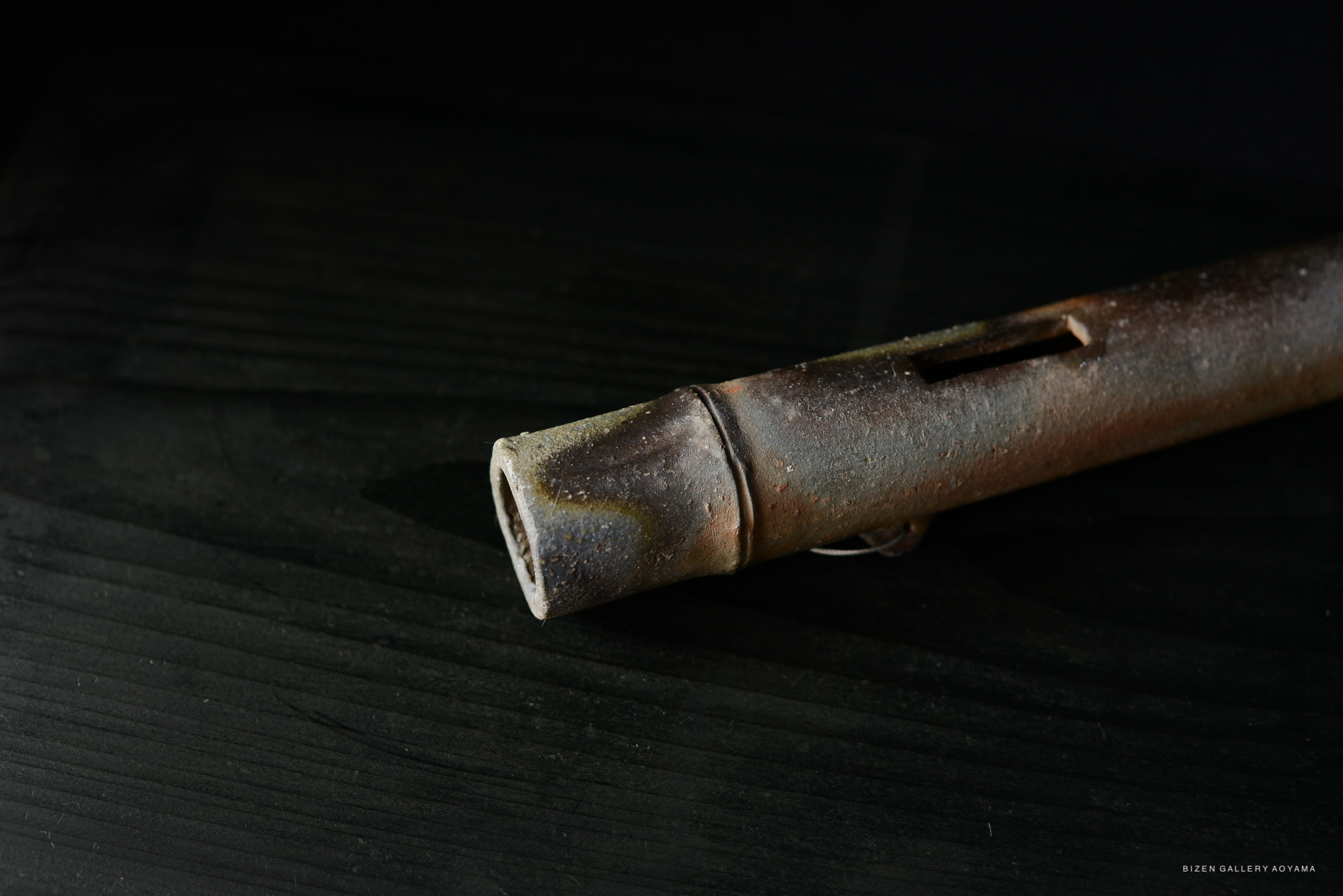 Close-up of a traditional ceramic flute with a textured surface, resting on a dark wooden background.