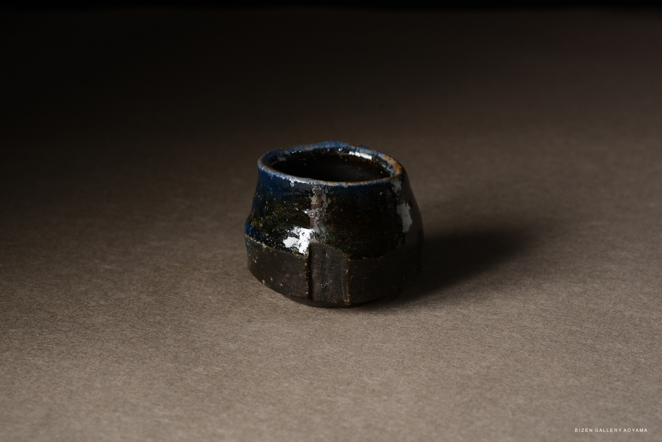 A handcrafted Bizen pottery piece with a dark brown and blue glaze, showcasing a unique, organic shape.