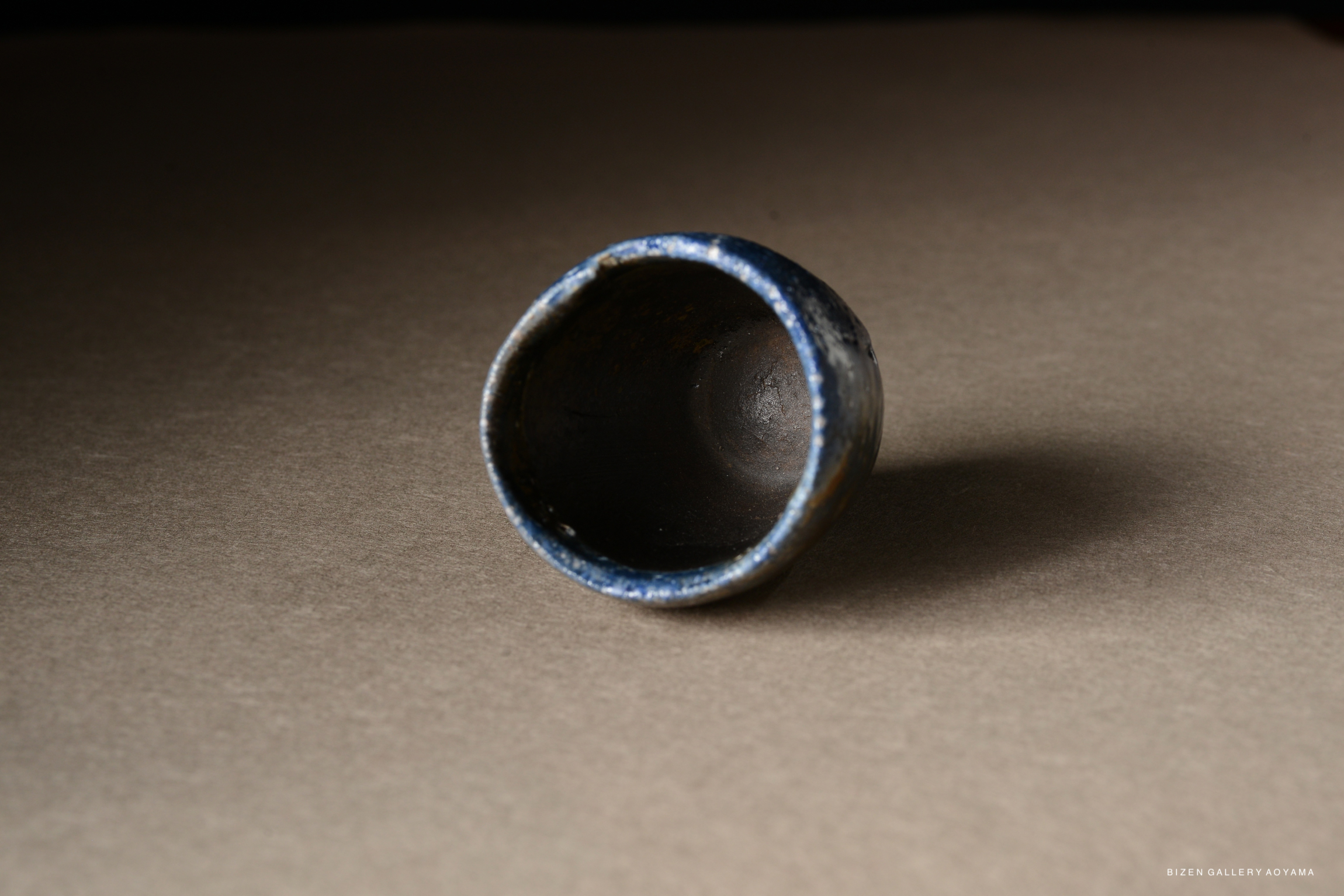A close-up of a blue ceramic cup placed on a brown surface, showcasing its interior and texture.