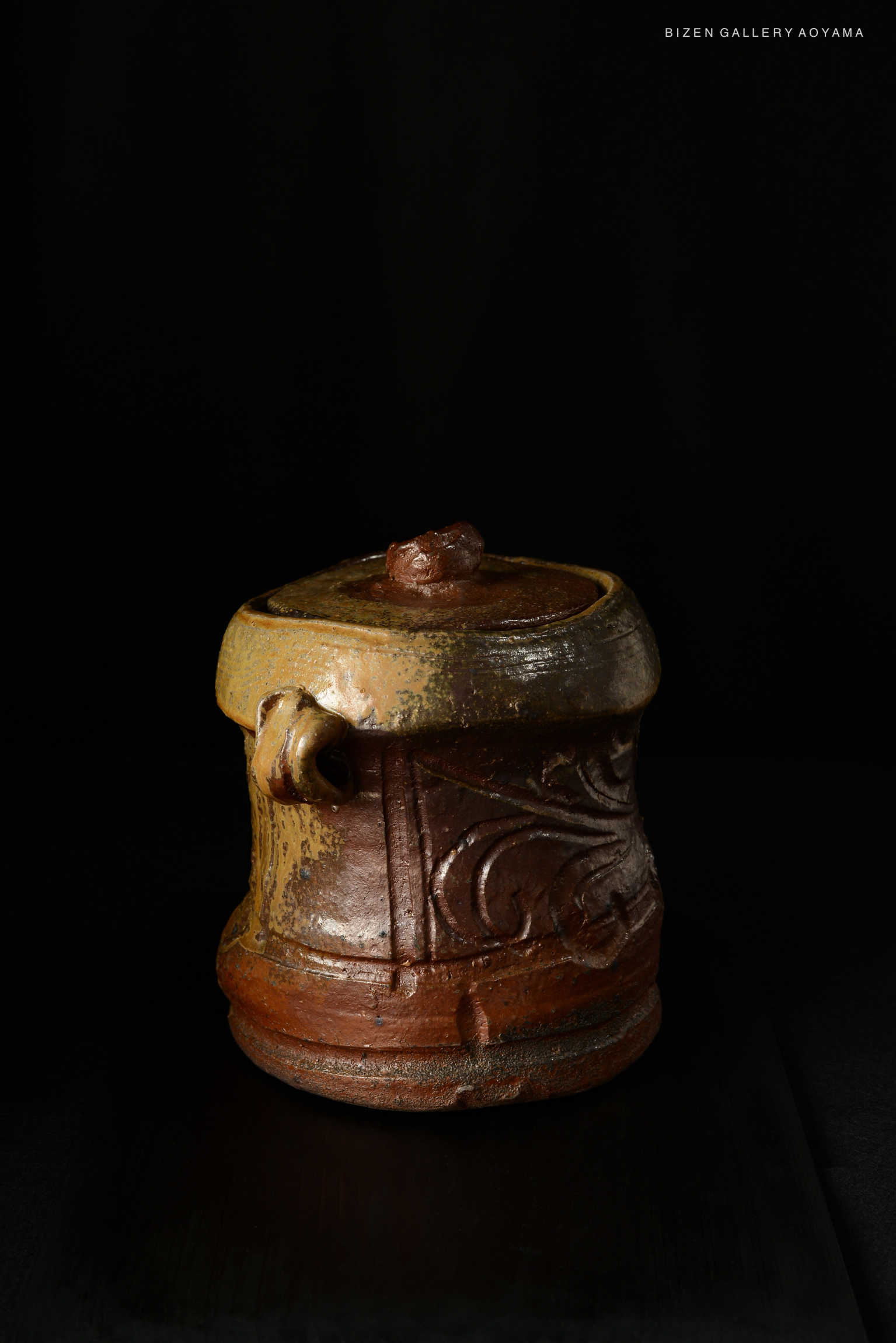 A Bizen Mizusashi ceramic water container featuring a textured and colorful design, shown against a black background.