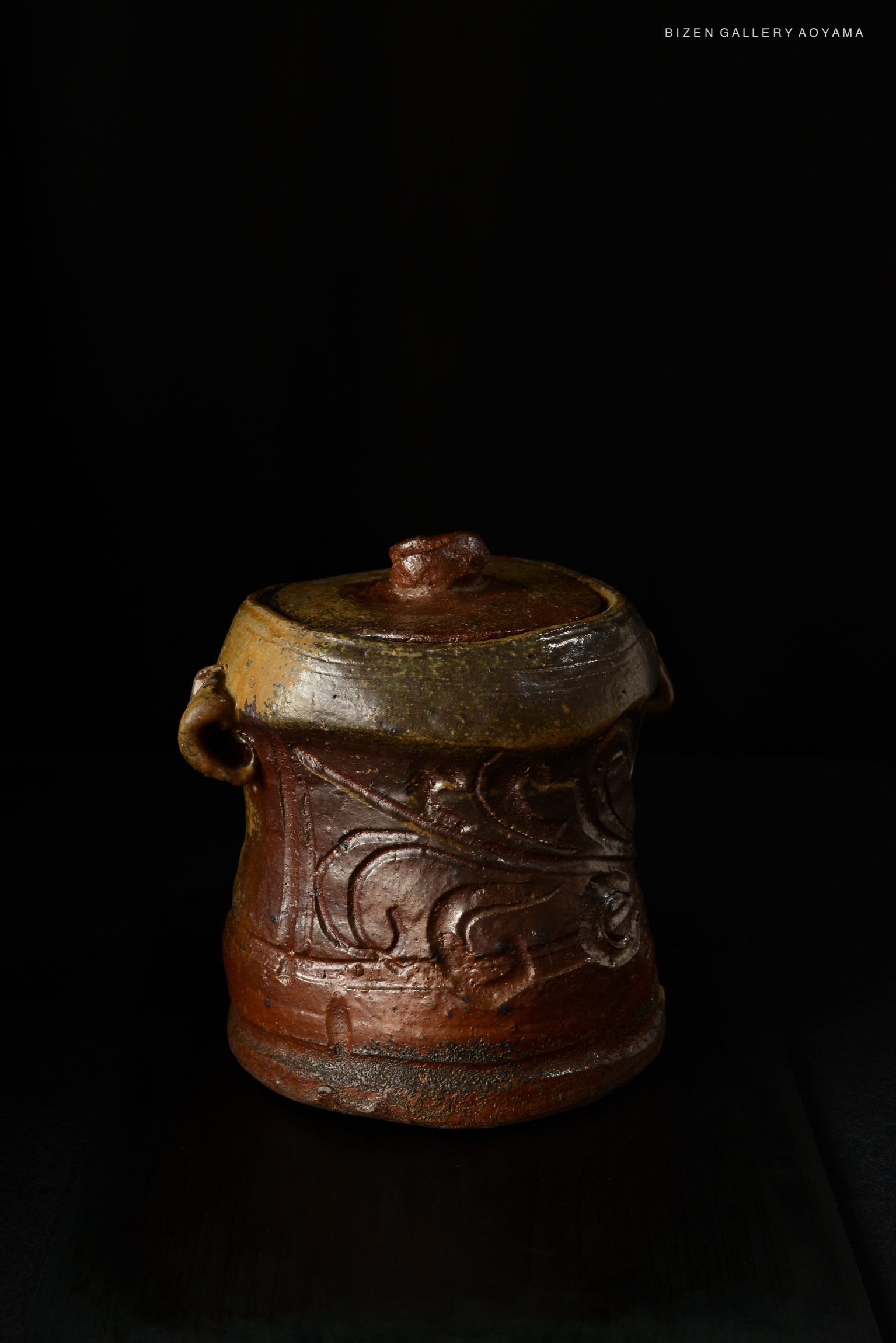 A Bizen Mizusashi, a traditional Japanese water container, featuring intricate designs and a rustic texture, displayed against a black background.