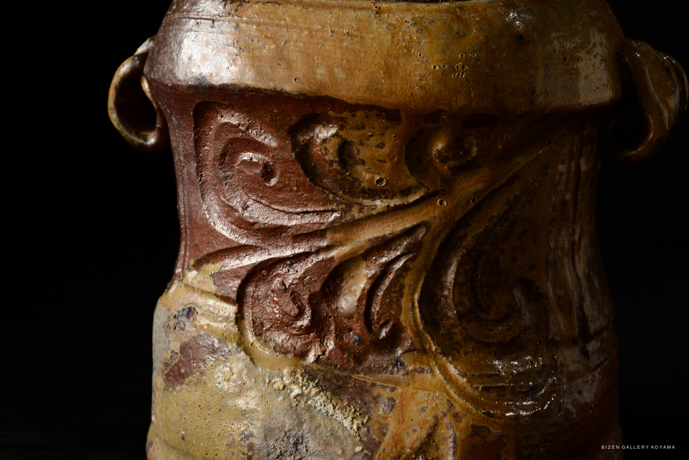 Close-up of a Bizen Mizusashi with intricate carvings and textured surface, showcasing earthy tones and craftsmanship.