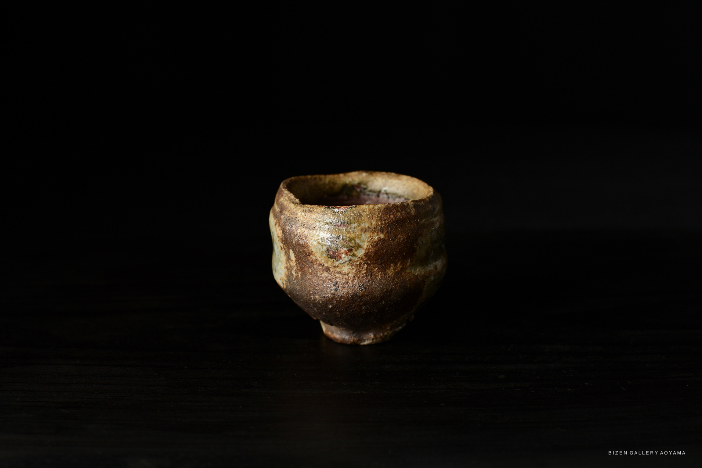 A traditional Bizen Guinomi sake cup by Naoe Koide, showcasing earthy tones and a unique, organic shape.