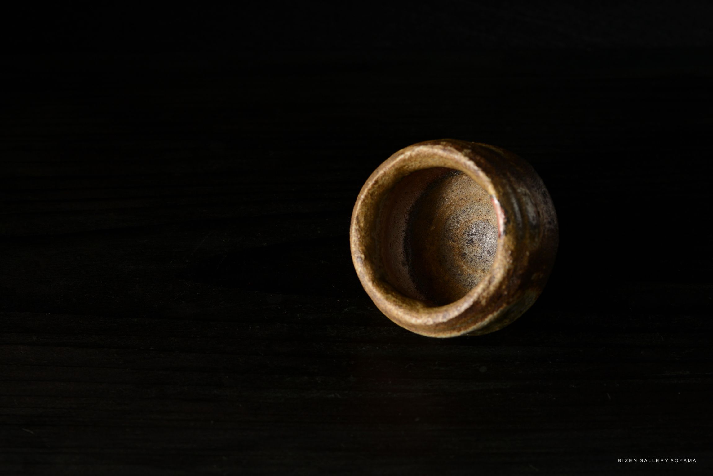 A close-up view of a Bizen Guinomi sake cup, showcasing its earthy texture and traditional Japanese craftsmanship.