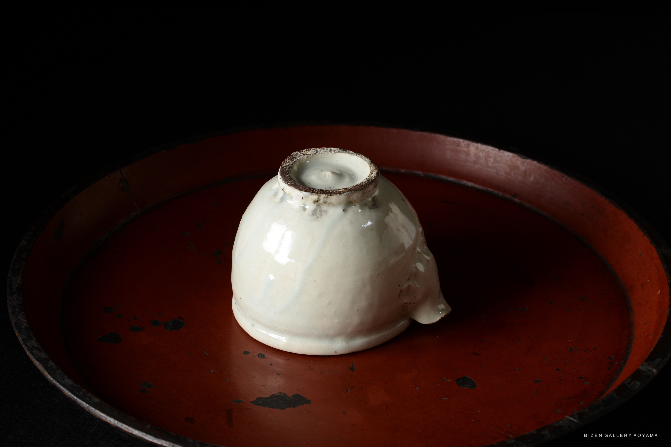 A white ceramic cup placed upside down on a rustic red tray with a dark background.