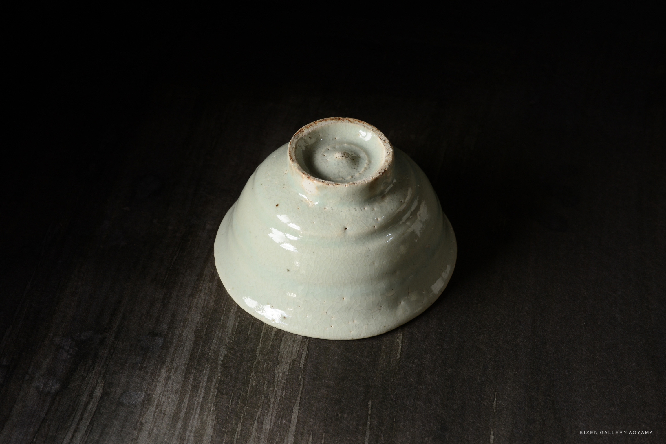 A close-up view of a light green ceramic bowl with a spiral design, set against a dark background.