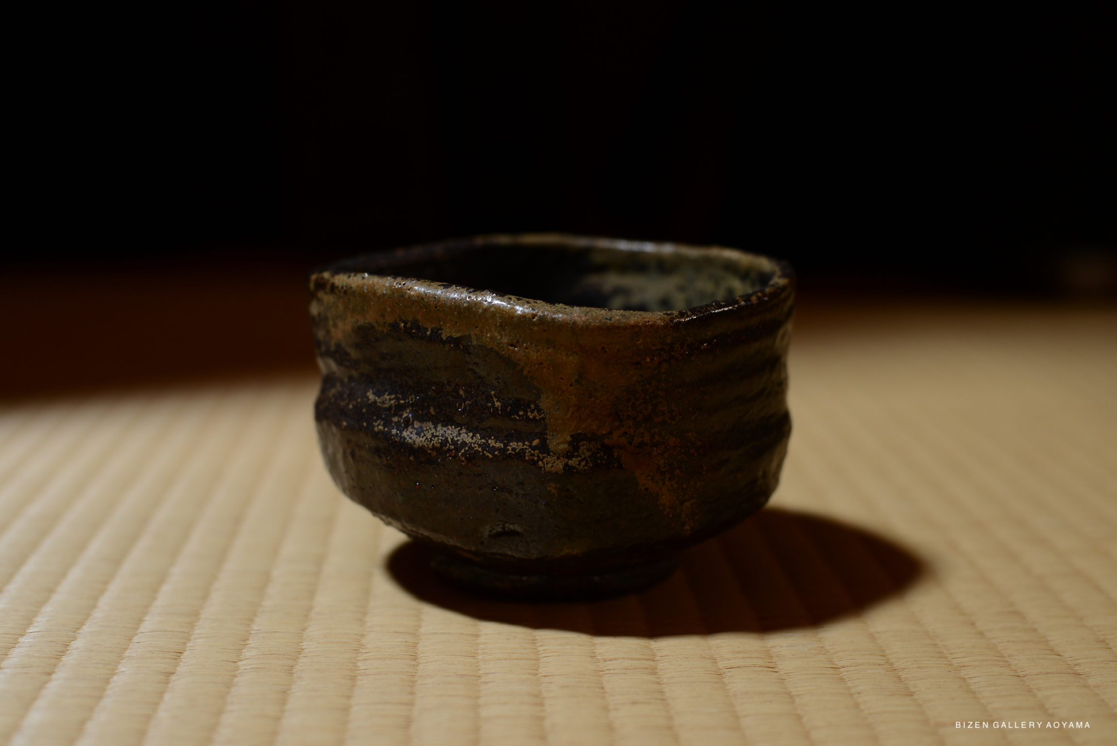 A close-up view of a traditional Japanese chawan (tea bowl) showcasing its earthy colors and irregular texture, representing craftsmanship influenced by the Sengoku period.