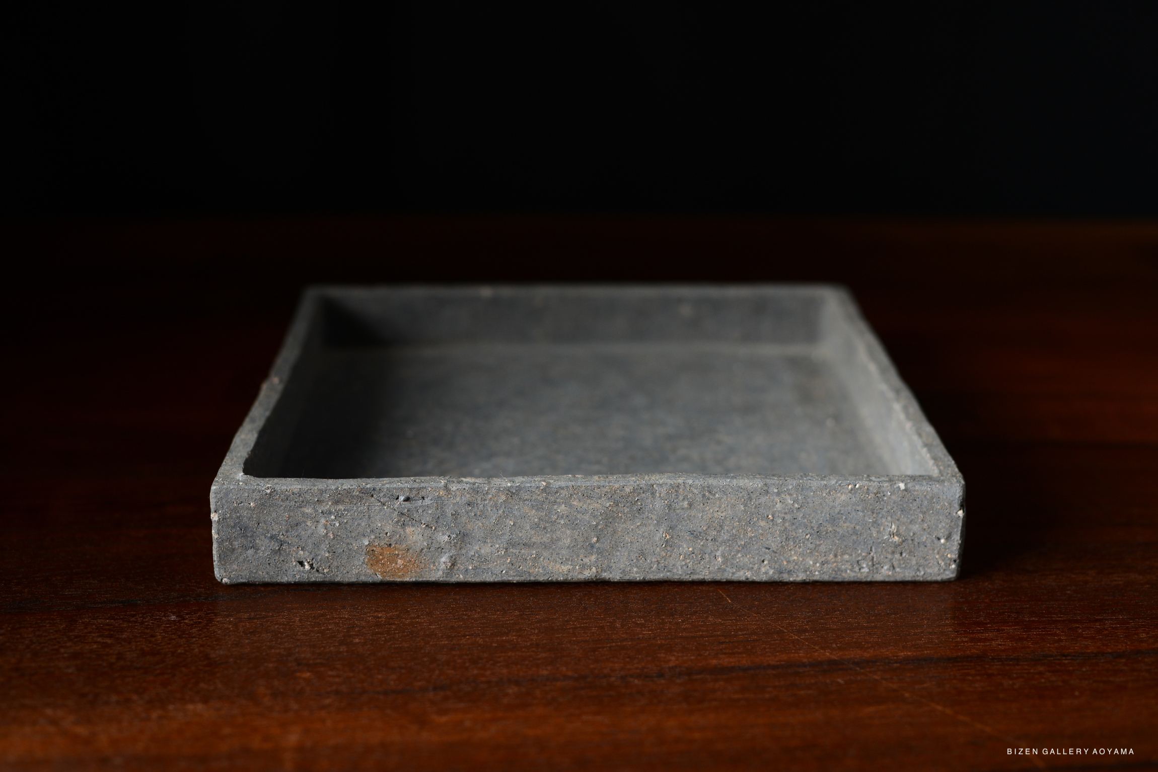 A simple square plate in a cool grey color with a clean design, suitable for dining.