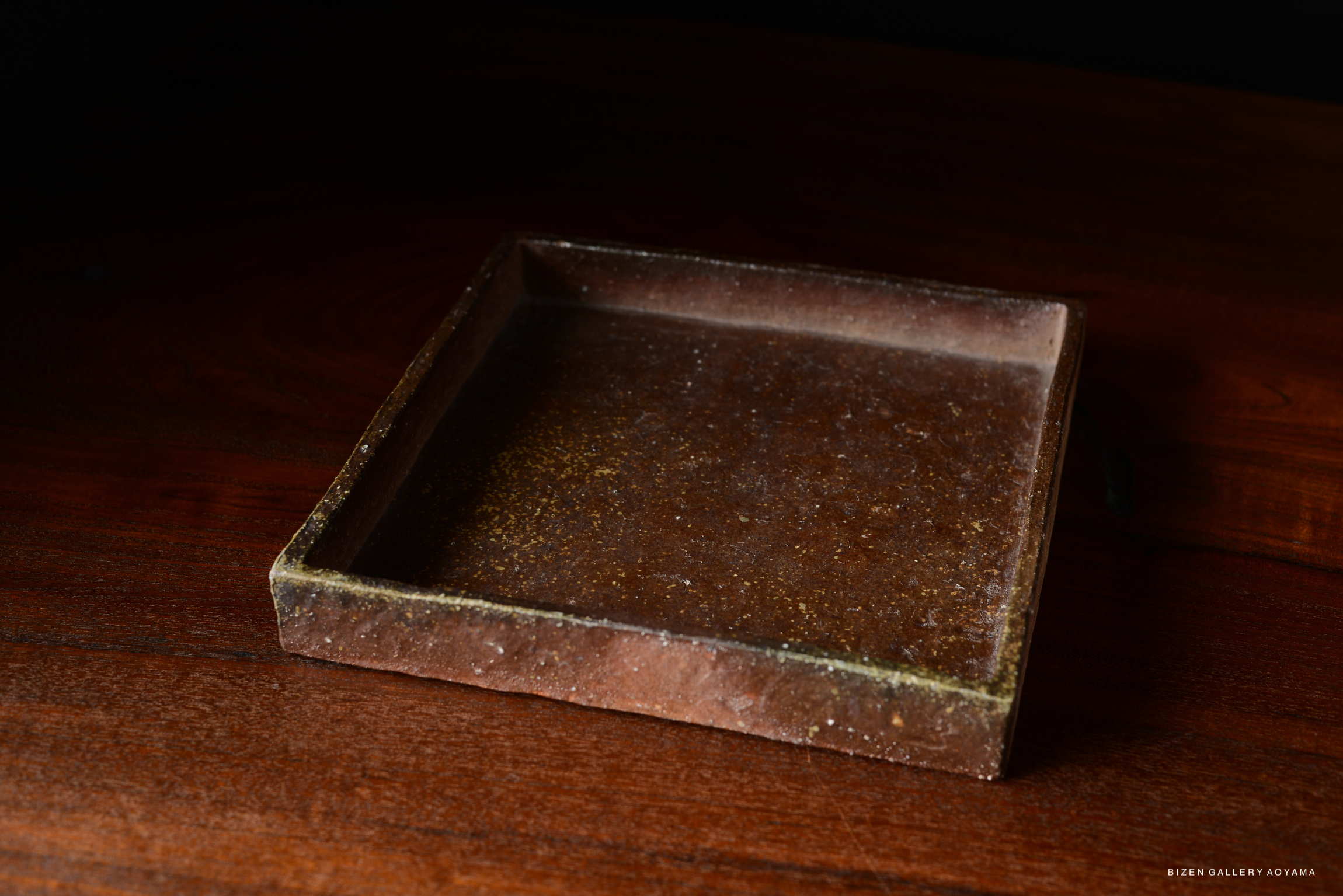 A simple and chic square plate in a classic brown color, showcased on a wooden table.