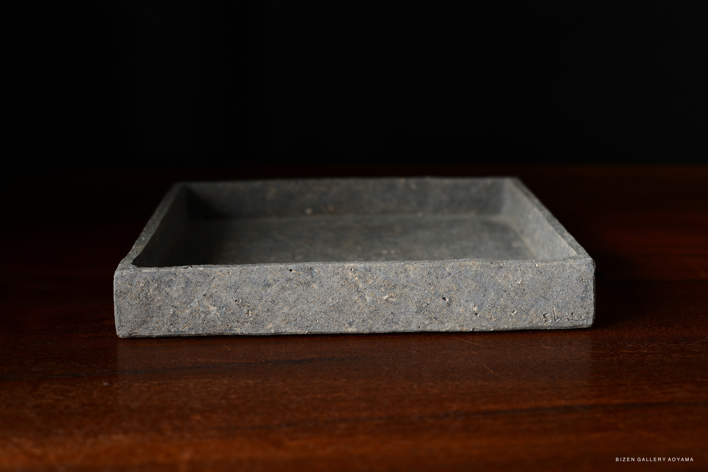 A simple and chic square plate in cool grey on a wooden surface.