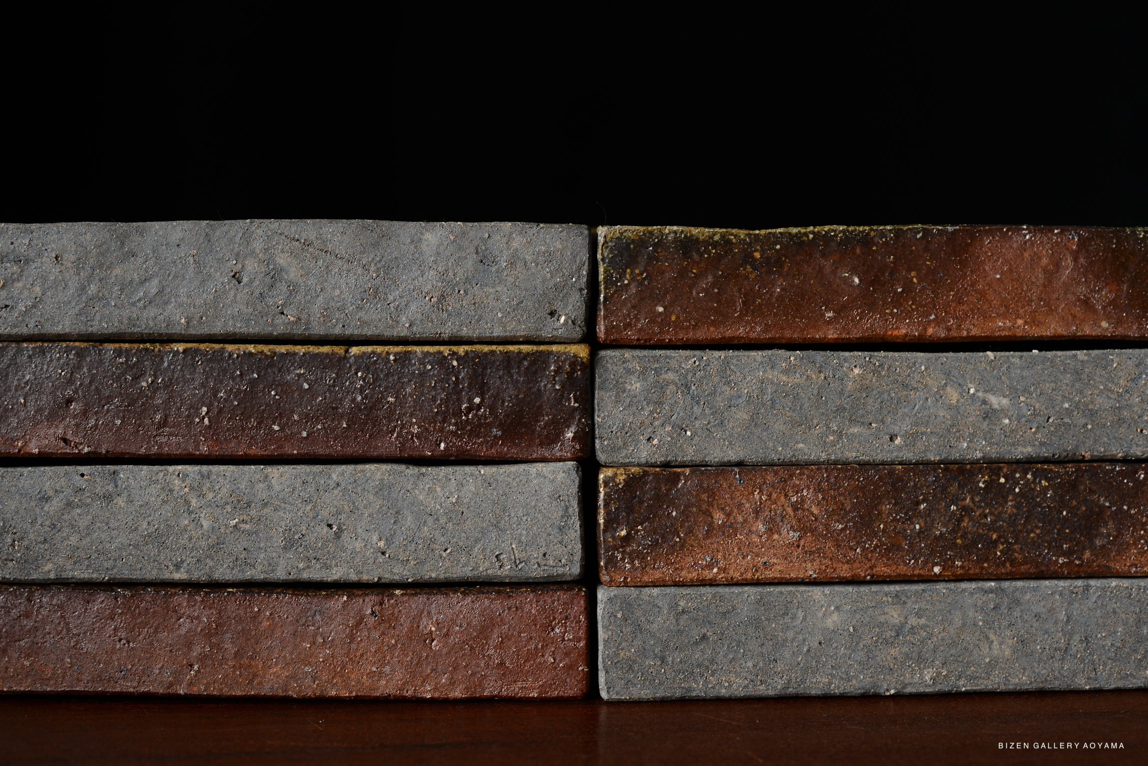 Stack of square plates in shades of brown and cool grey, showcasing a minimalist design against a dark background.