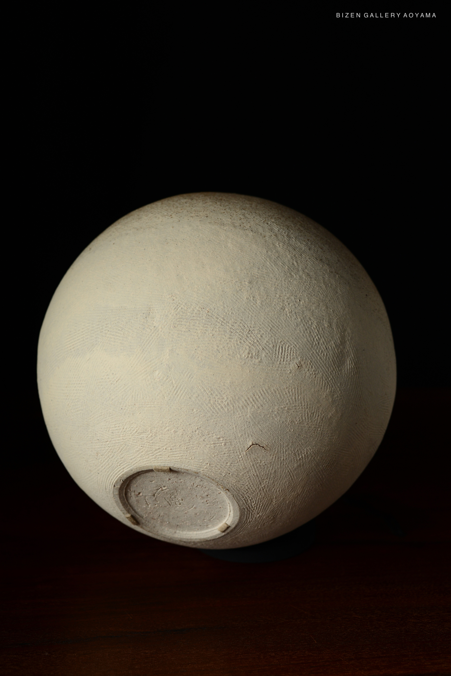 A round Bizen pottery vase with a textured surface, displayed against a black background.