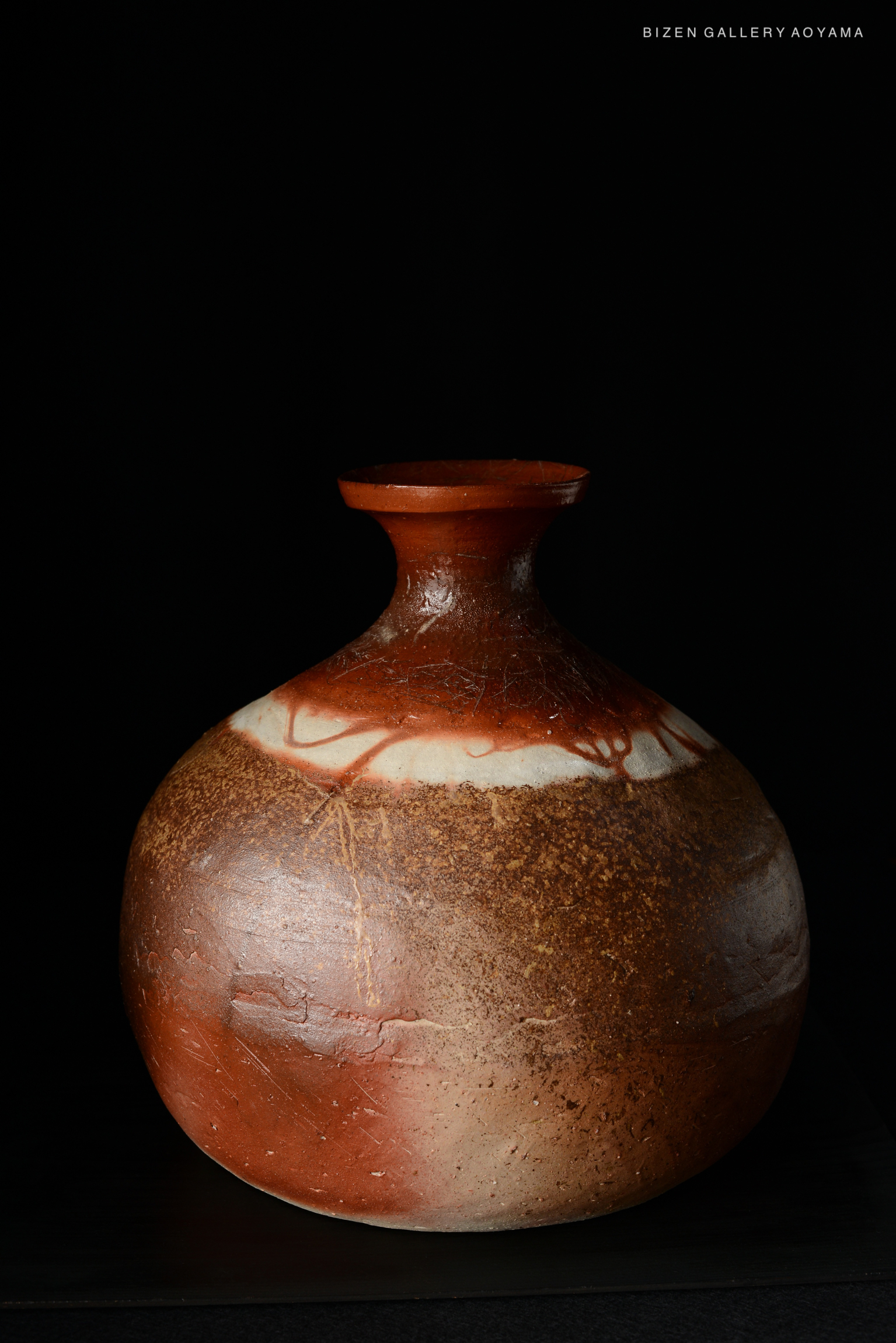 A Bizen pottery Tokkuri, characterized by its rounded body and narrow neck, featuring natural earthy tones and a distinctive glaze finish, set against a black background.