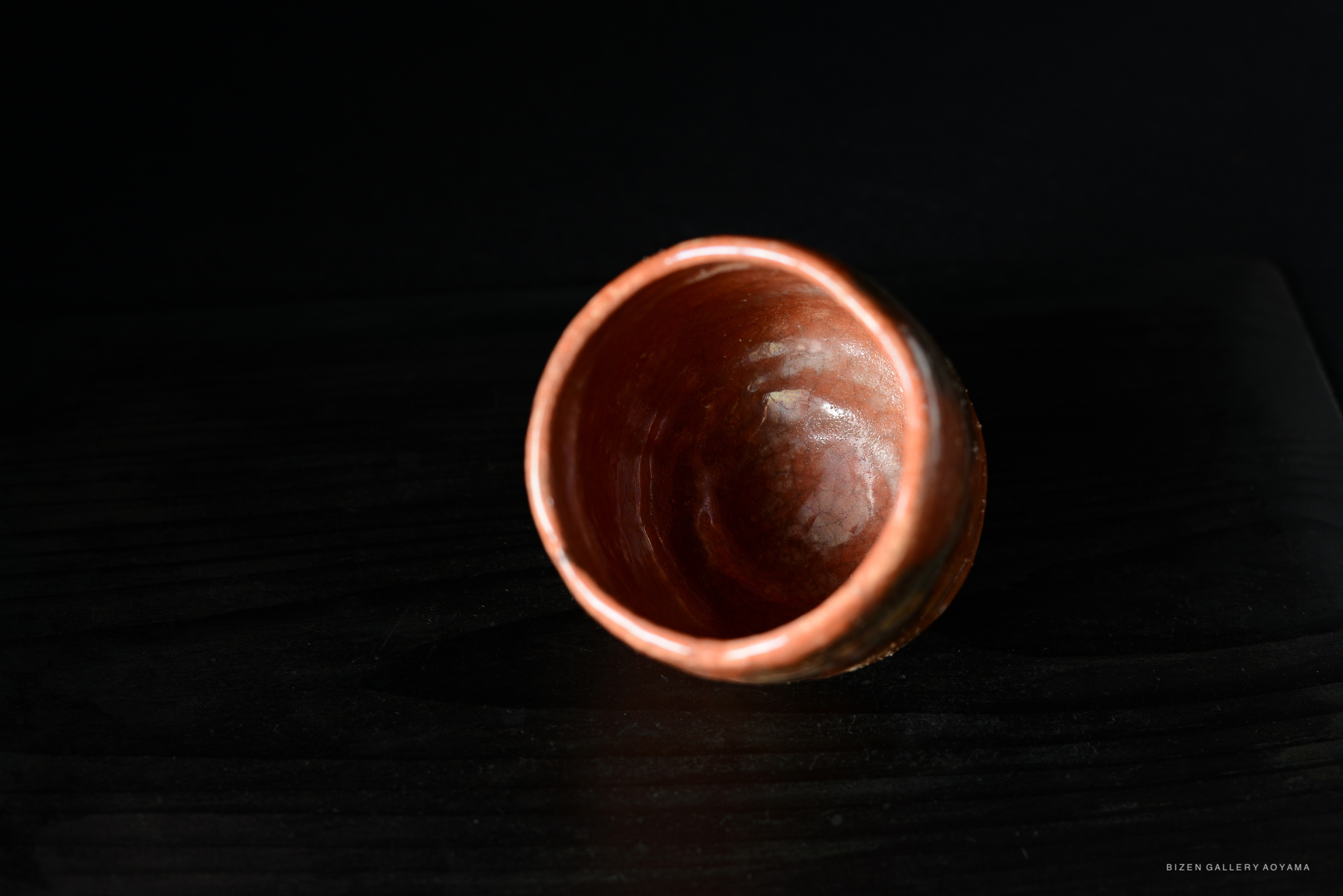 A close-up view of a traditional Japanese tea bowl, showcasing its interior and unique ceramic texture, with a dark background.