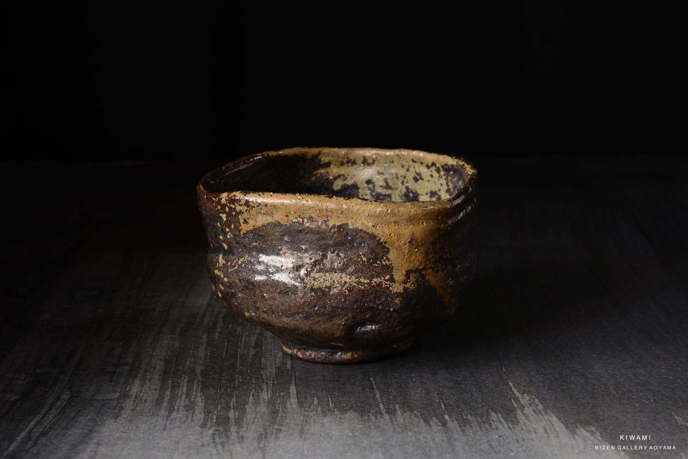 A rustic ceramic bowl with an earthy texture and dark glaze, placed on a textured dark surface.