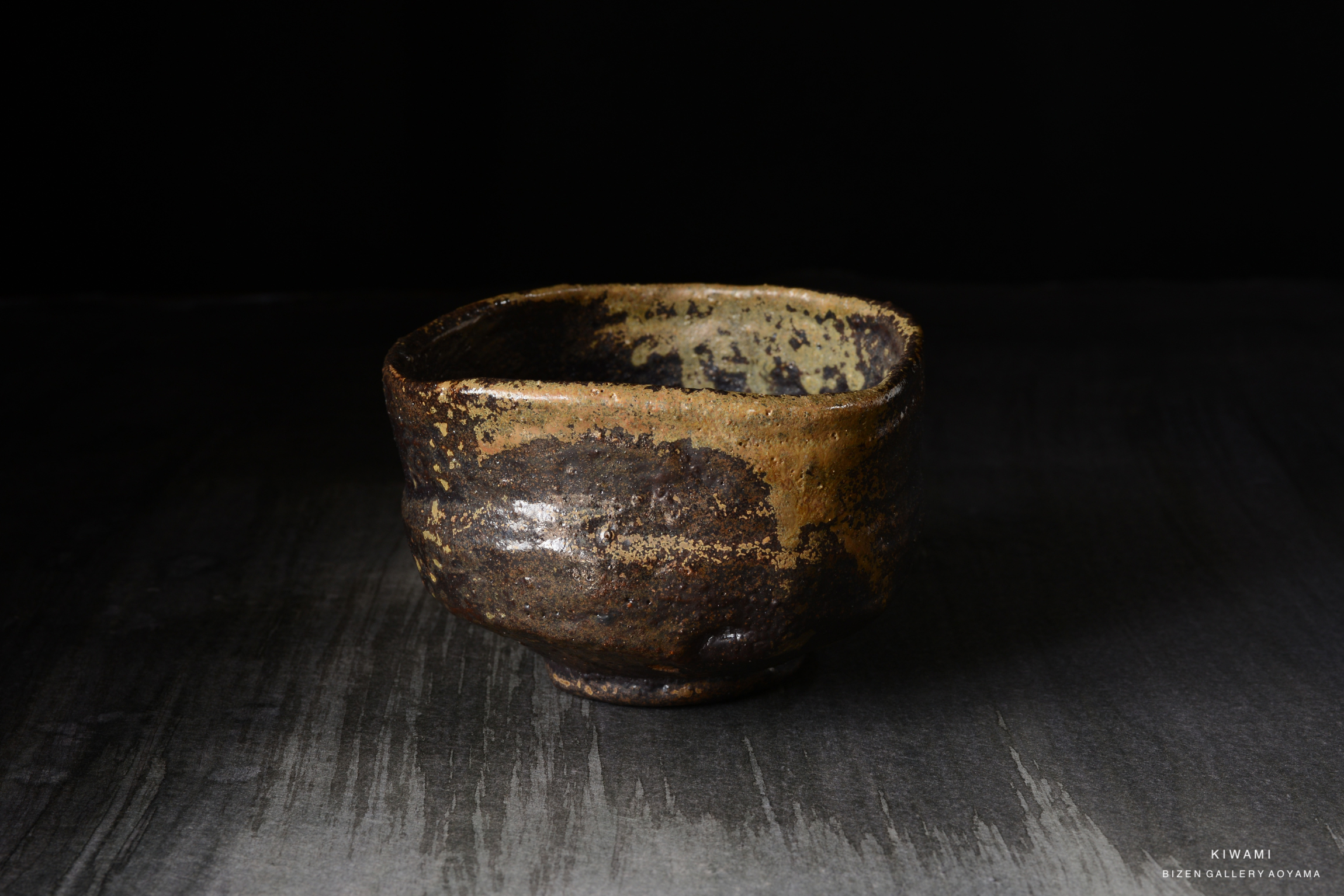 A rustic ceramic bowl with a textured surface and earthy tones, set against a dark background.