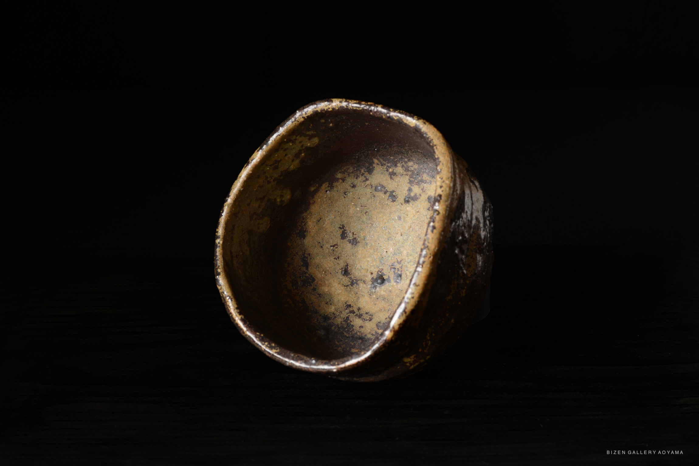 A close-up image of a rustic ceramic bowl with a textured surface, set against a dark background.