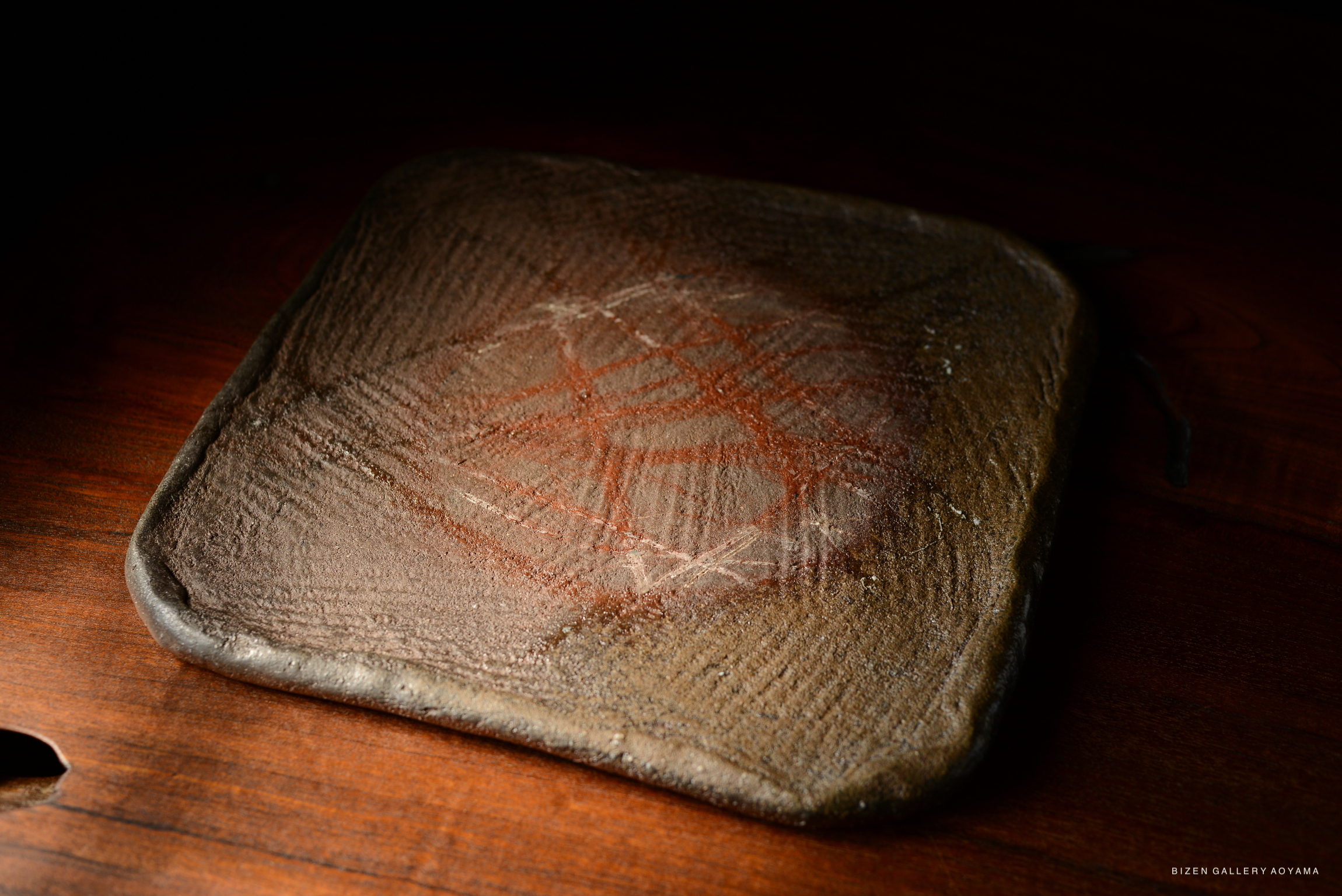 An artistic stone slab with intricate red and white markings, placed on a wooden surface.