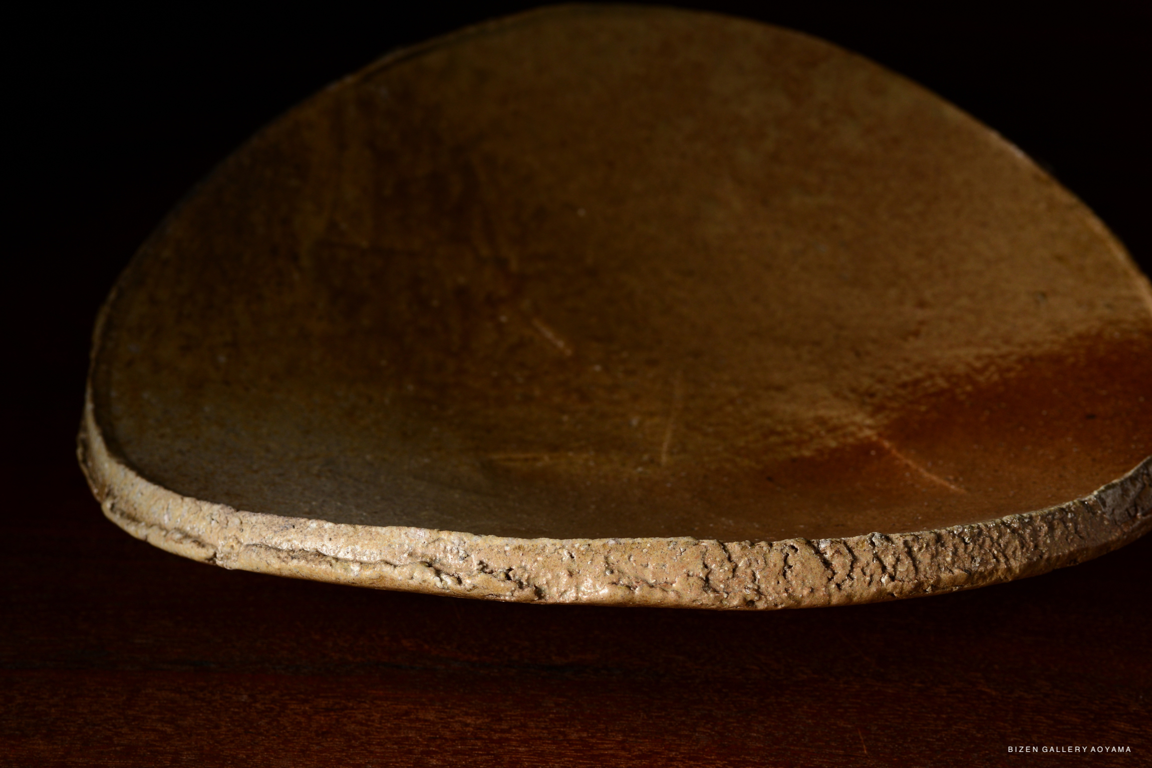 Close-up view of a textured ceramic plate, highlighting its uneven edge and matte finish.