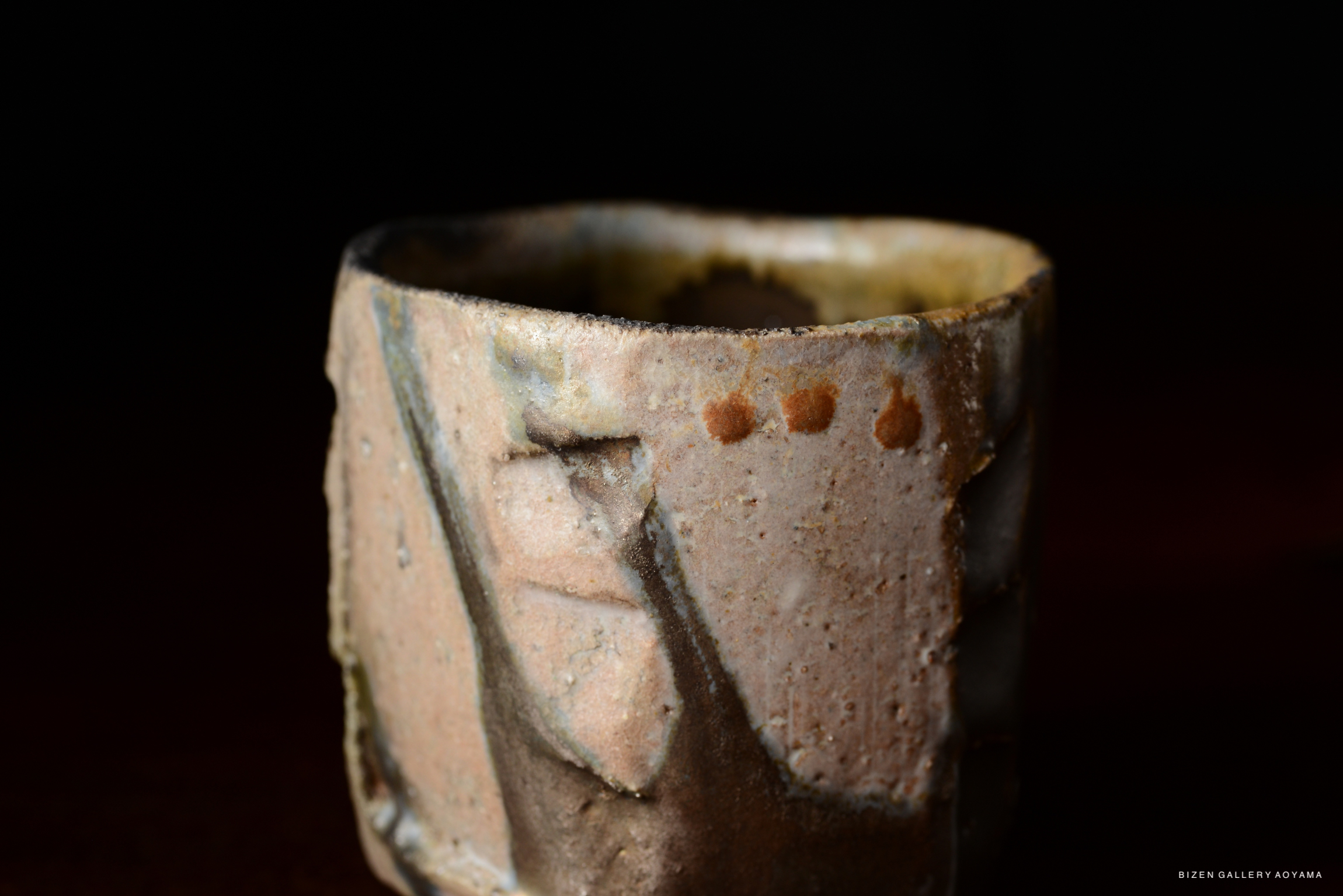 Close-up of an artistic ceramic tea cup with a textured surface, displaying natural earthy tones and intricate details.
