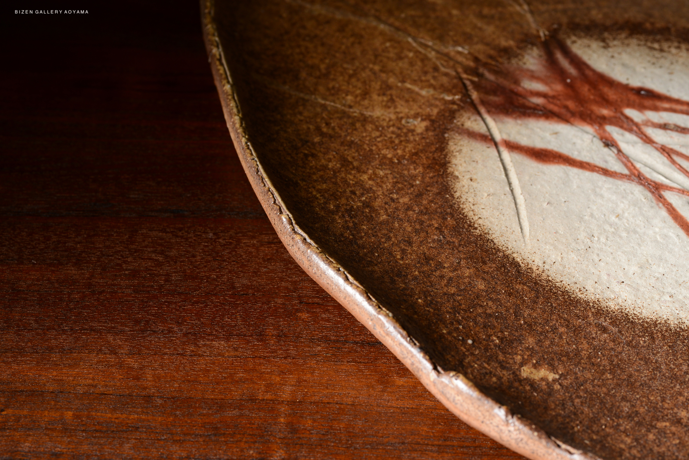 Close-up of a ceramic plate with a textured brown surface and a subtle white design, placed on a wooden table.