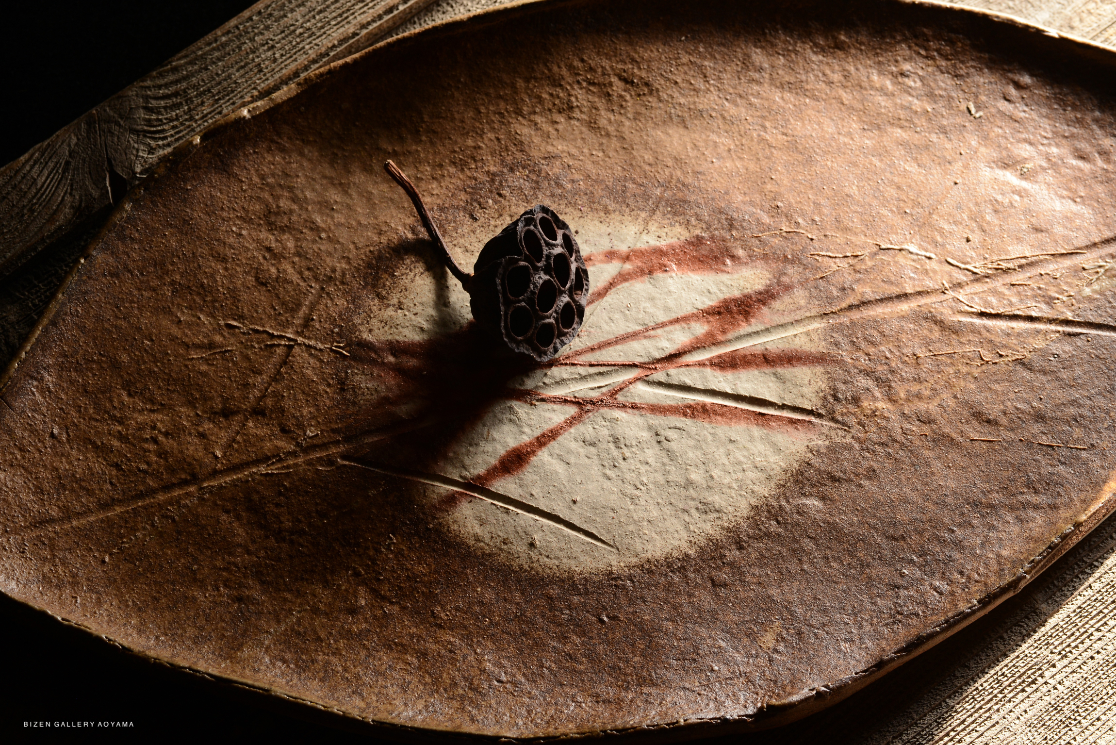 A beautifully crafted platter designed to resemble a leaf, placed on a textured surface with a natural aesthetic.