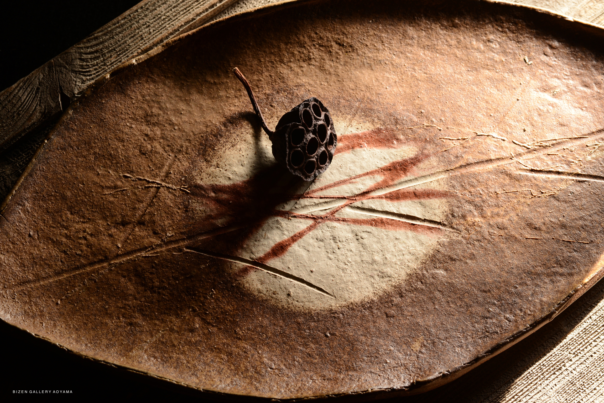 A unique ceramic platter shaped like a leaf, featuring intricate textures and patterns.