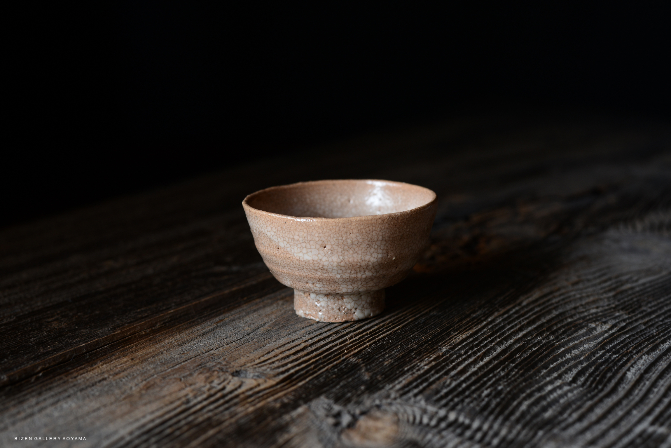 A simple, shallow ceramic bowl with a textured surface, placed on a dark wooden table.