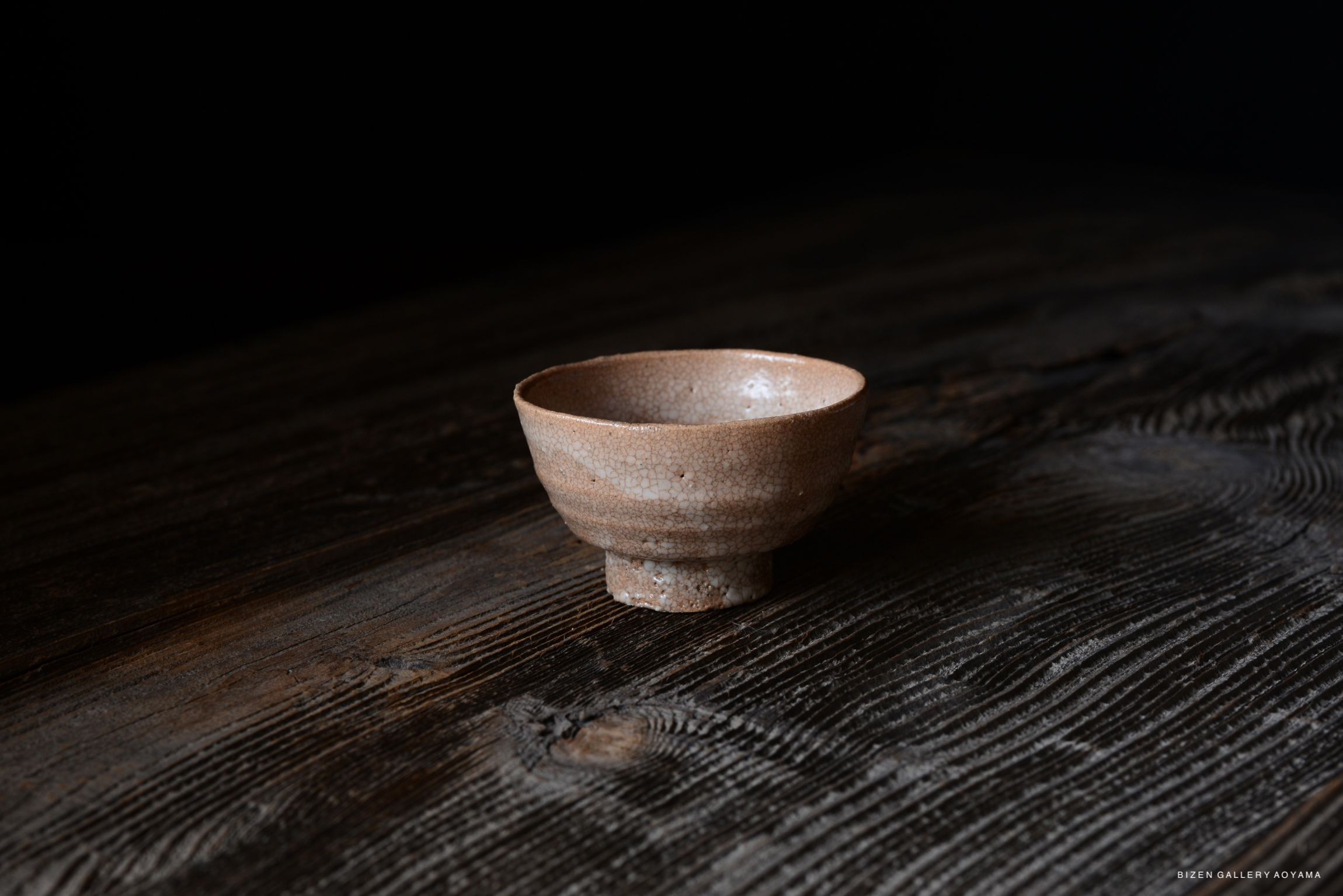 A close-up view of a ceramic bowl with a textured surface, set against a dark background.