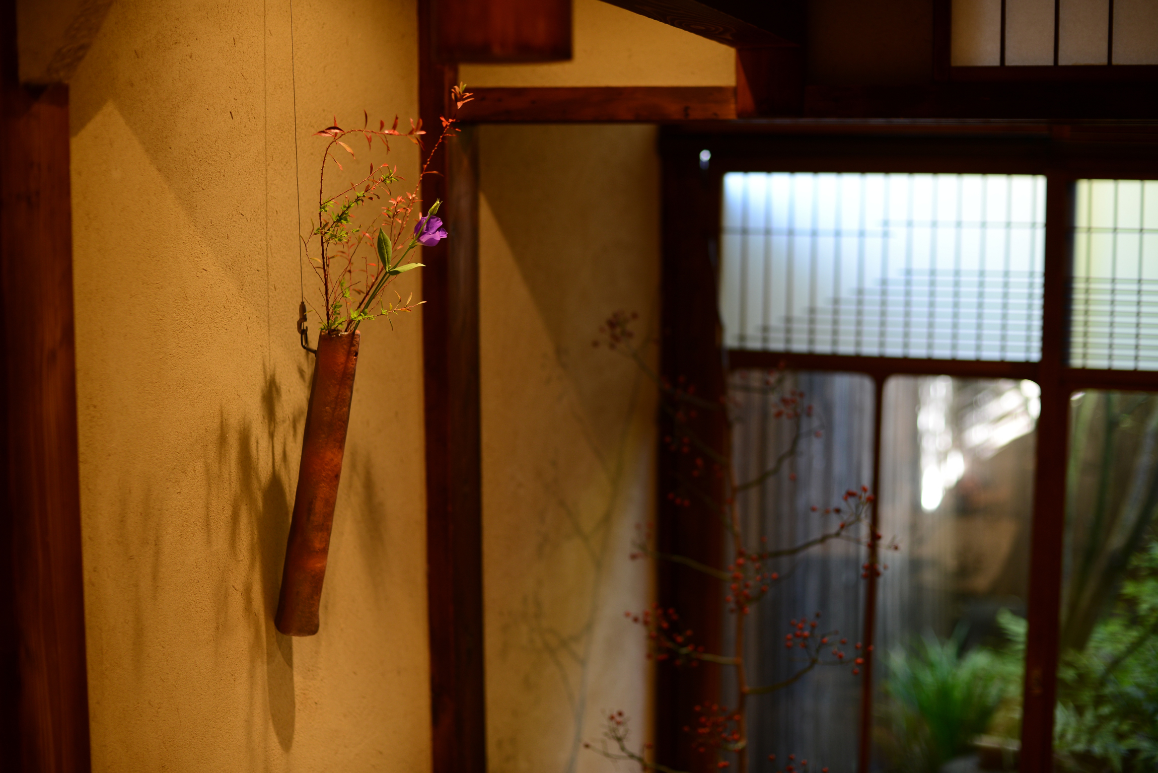 A rustic Bizen Kakehanaire with colorful flowers displayed in a traditional Japanese setting.