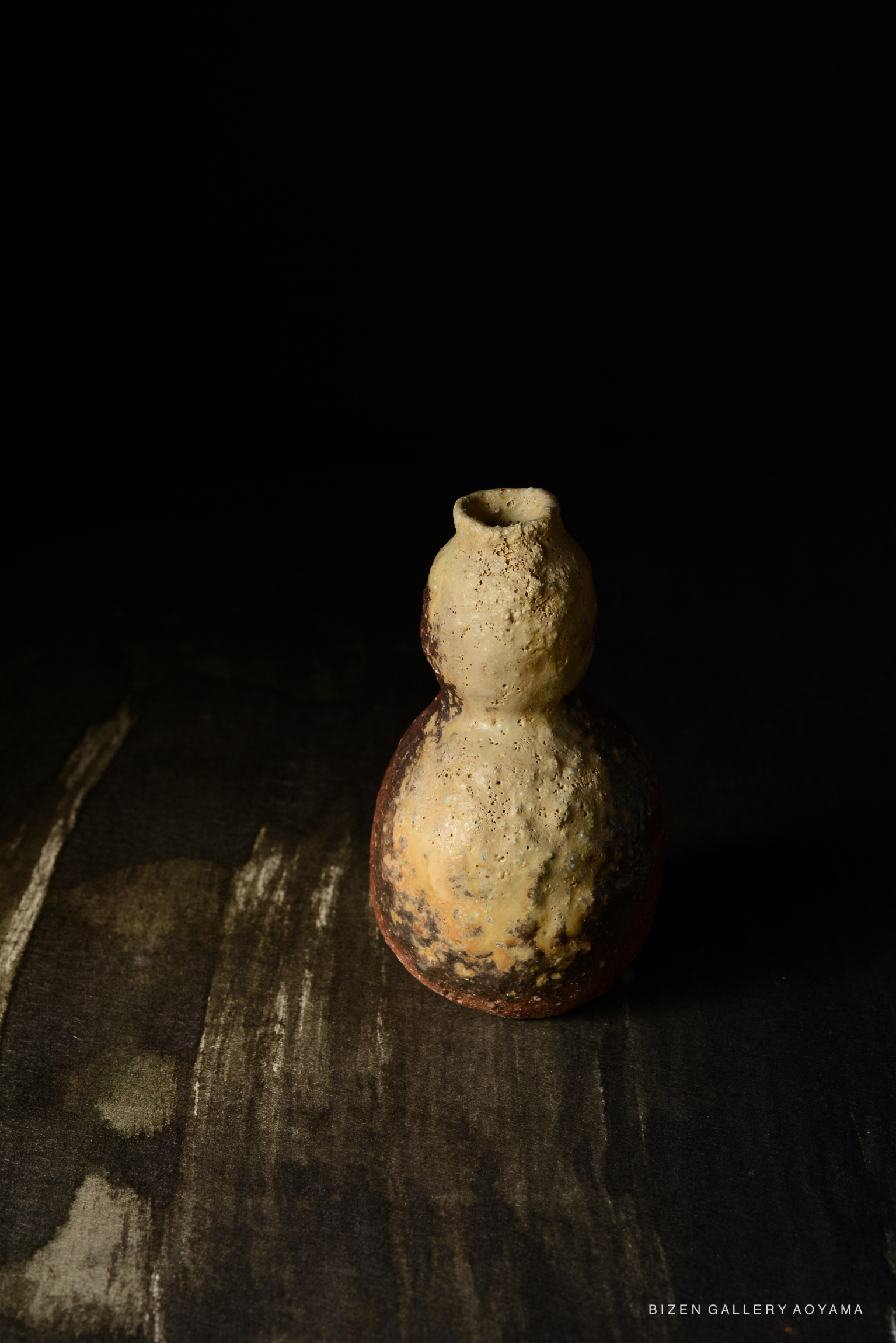 黒い背景に置かれた独特な形状の備前焼の陶器。
