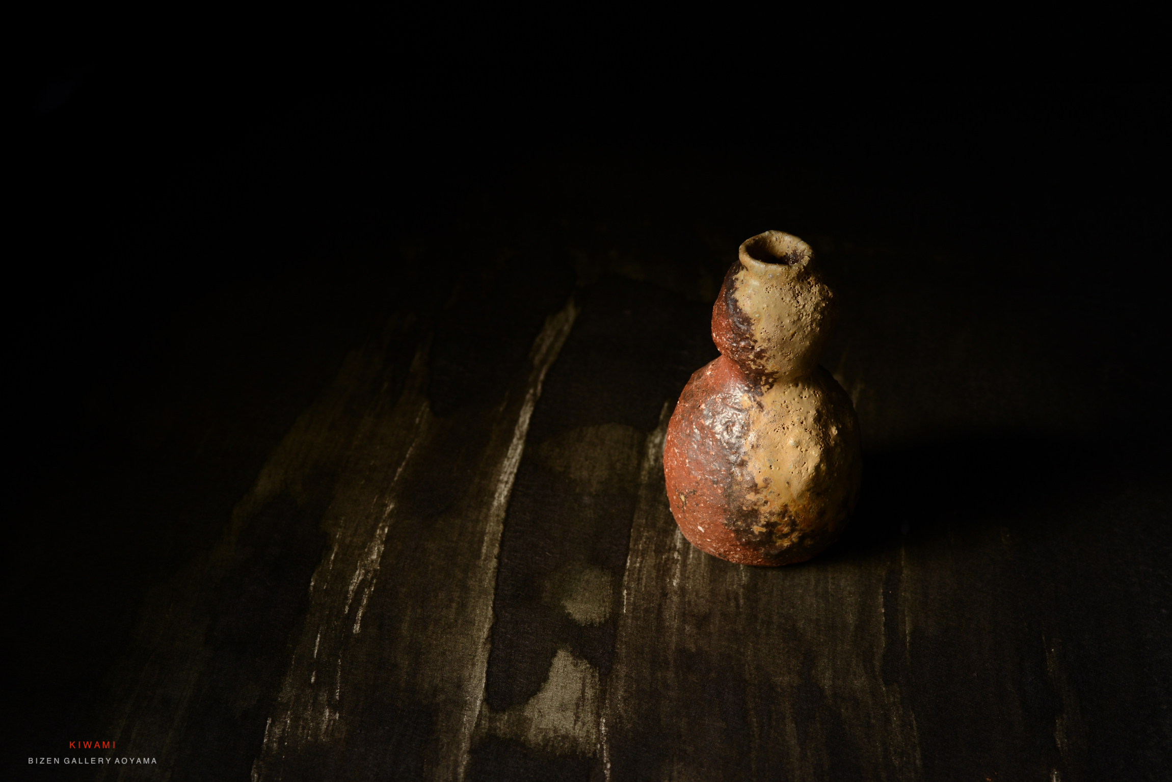 暗い背景に置かれた独特の形状の陶器の壺